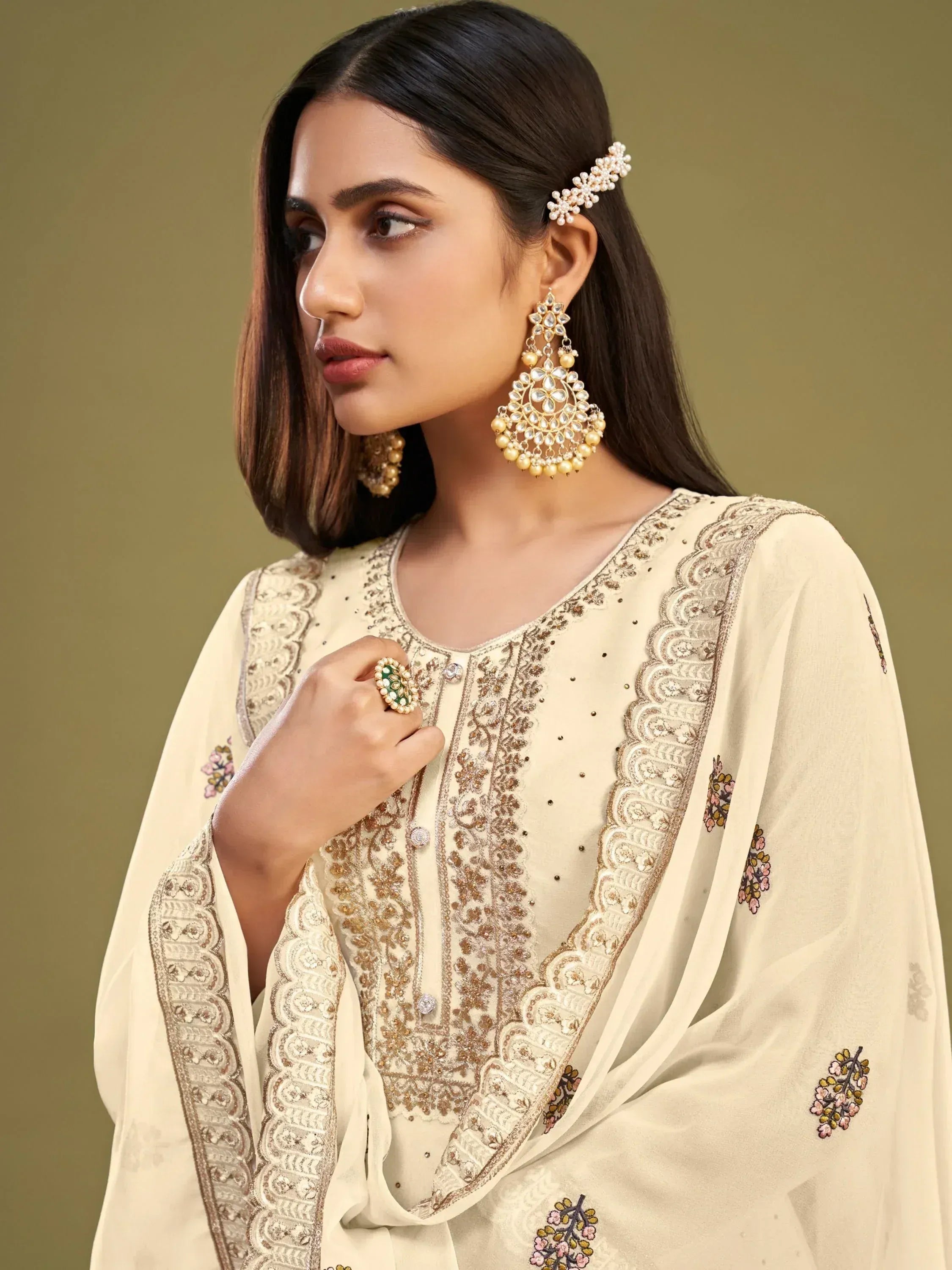 Elegant cream embroidered salwar kameez with gold detailing, floral motifs, and statement jhumka earrings for Indian ethnic wear.