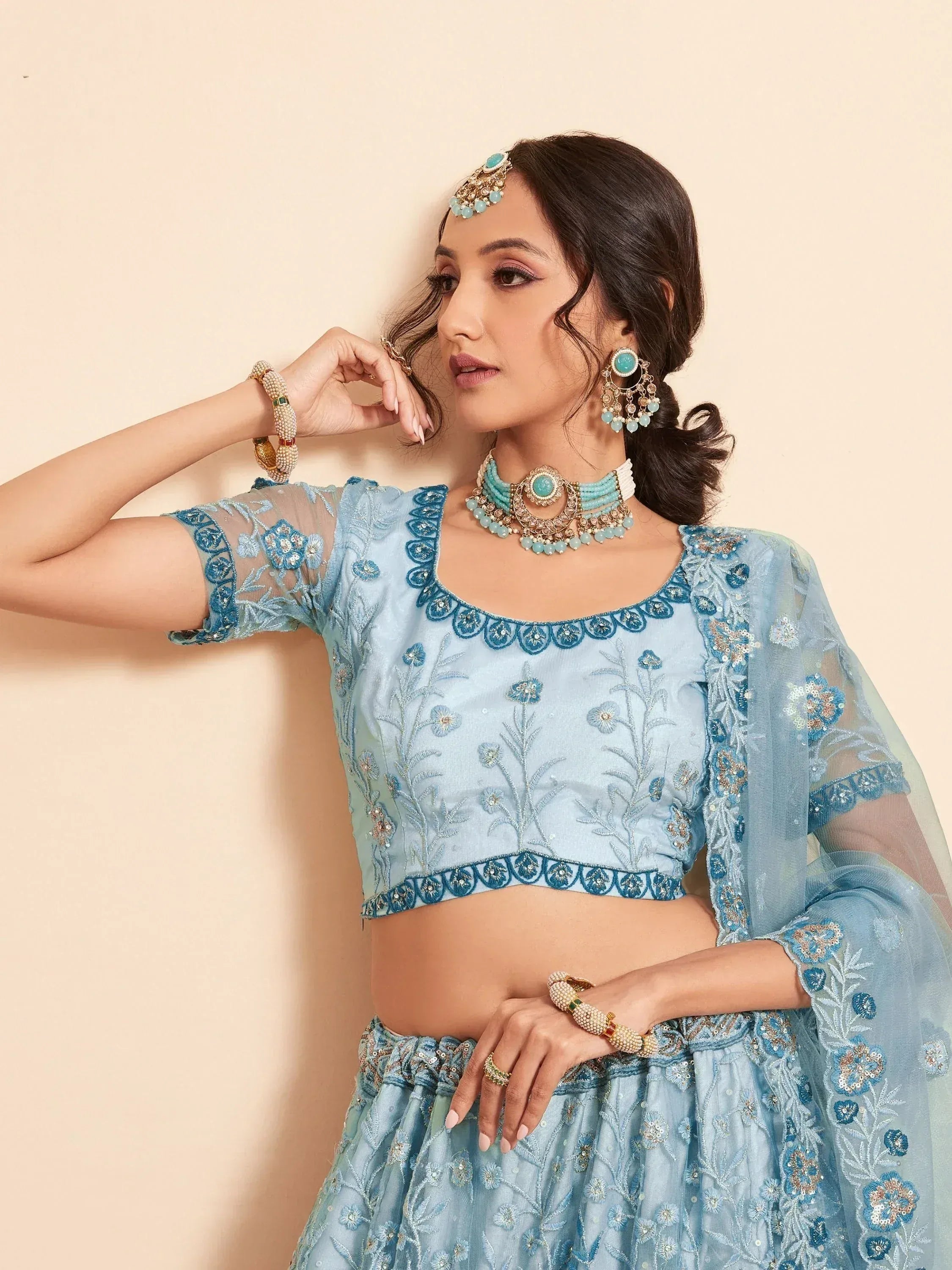 Light blue embroidered lehenga choli with floral detailing and matching jewelry for Indian ethnic wear
