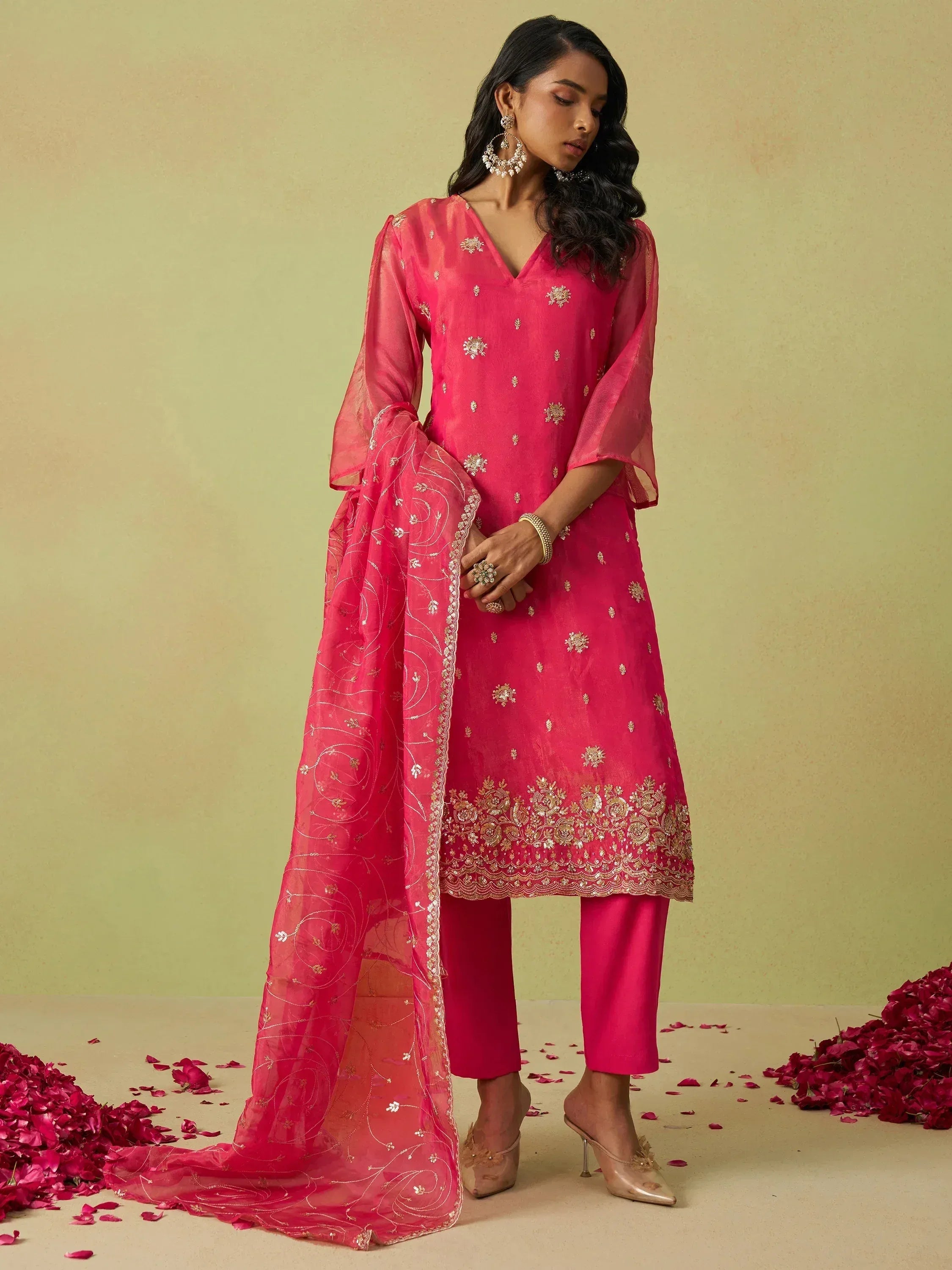 Pink embroidered salwar kameez with sheer dupatta, gold detailing, and rose petals
