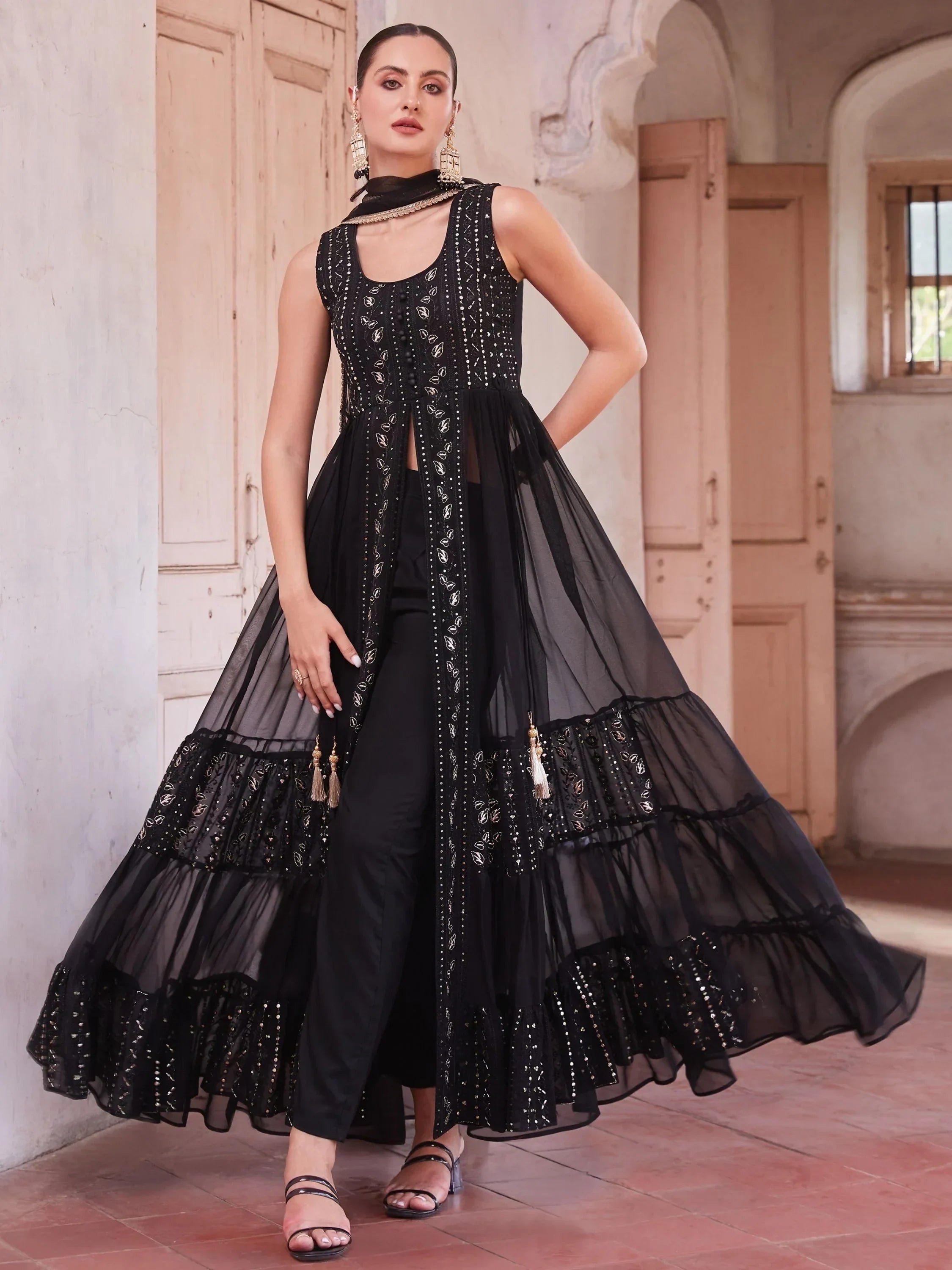 Woman wearing a black embroidered ethnic gown with sheer overlay and churidar in heritage setting