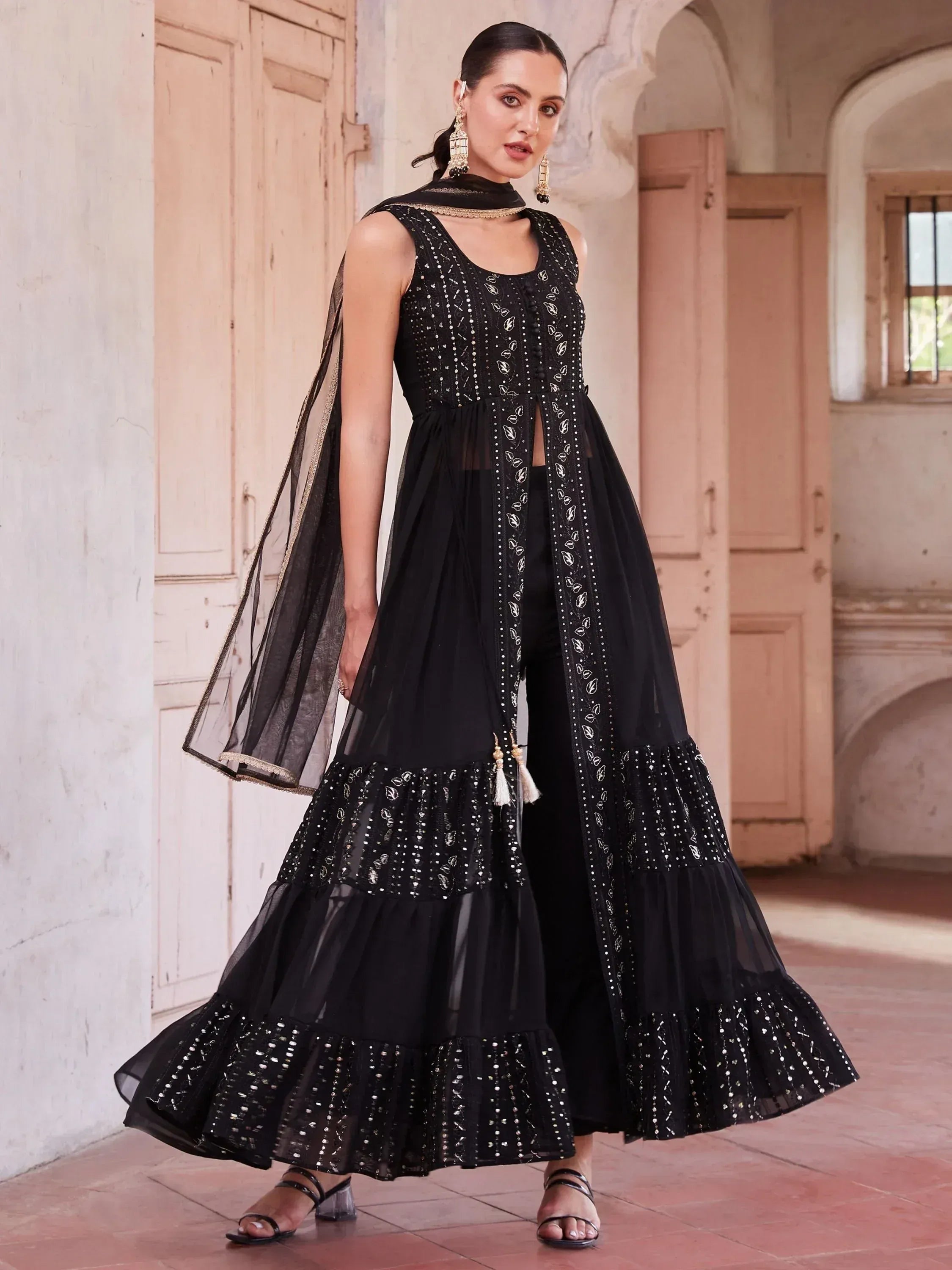 Woman wearing a black embroidered ethnic gown with dupatta in a traditional setting
