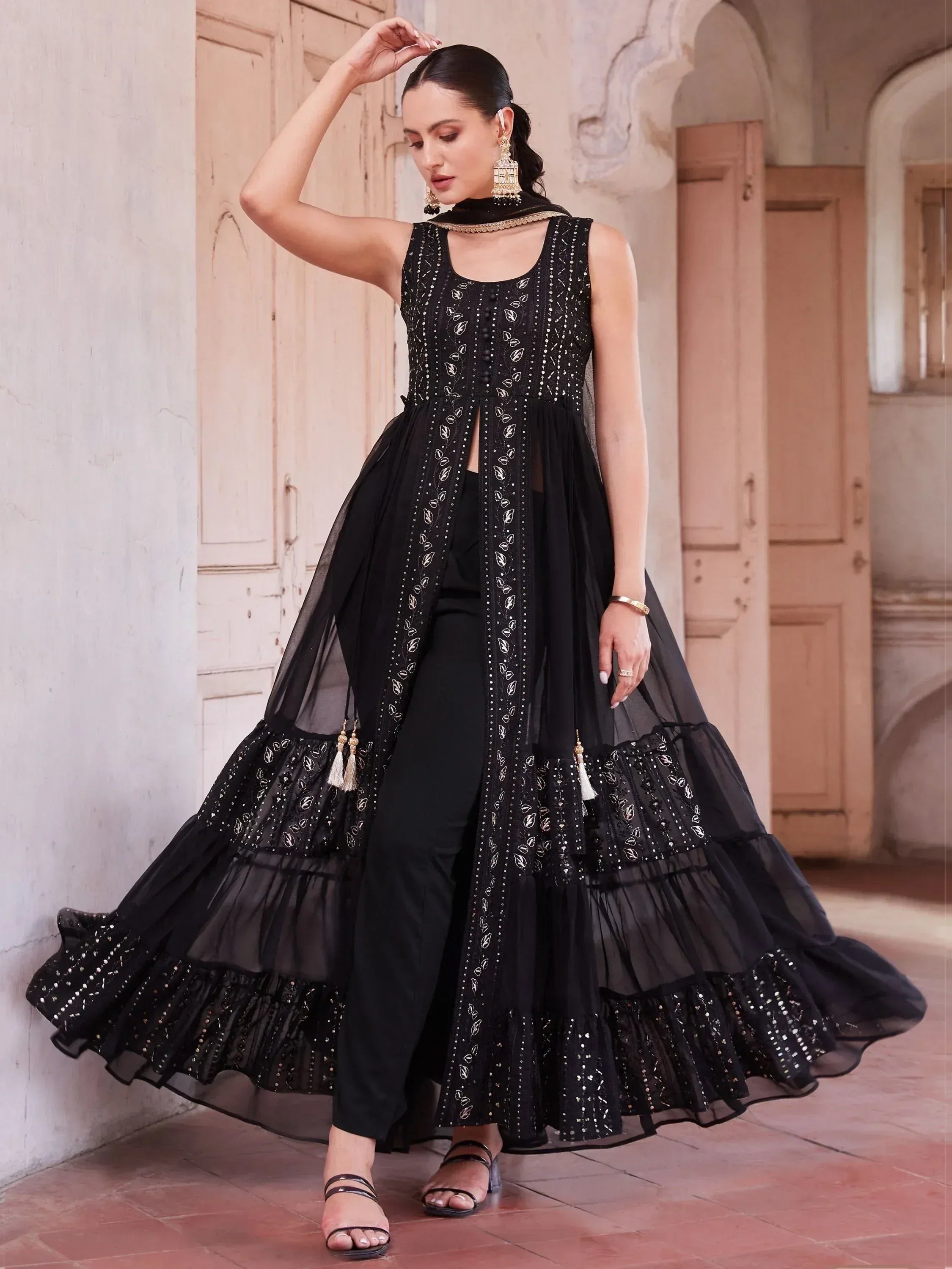 Woman wearing a designer black embroidered ethnic gown with sheer layers indoors