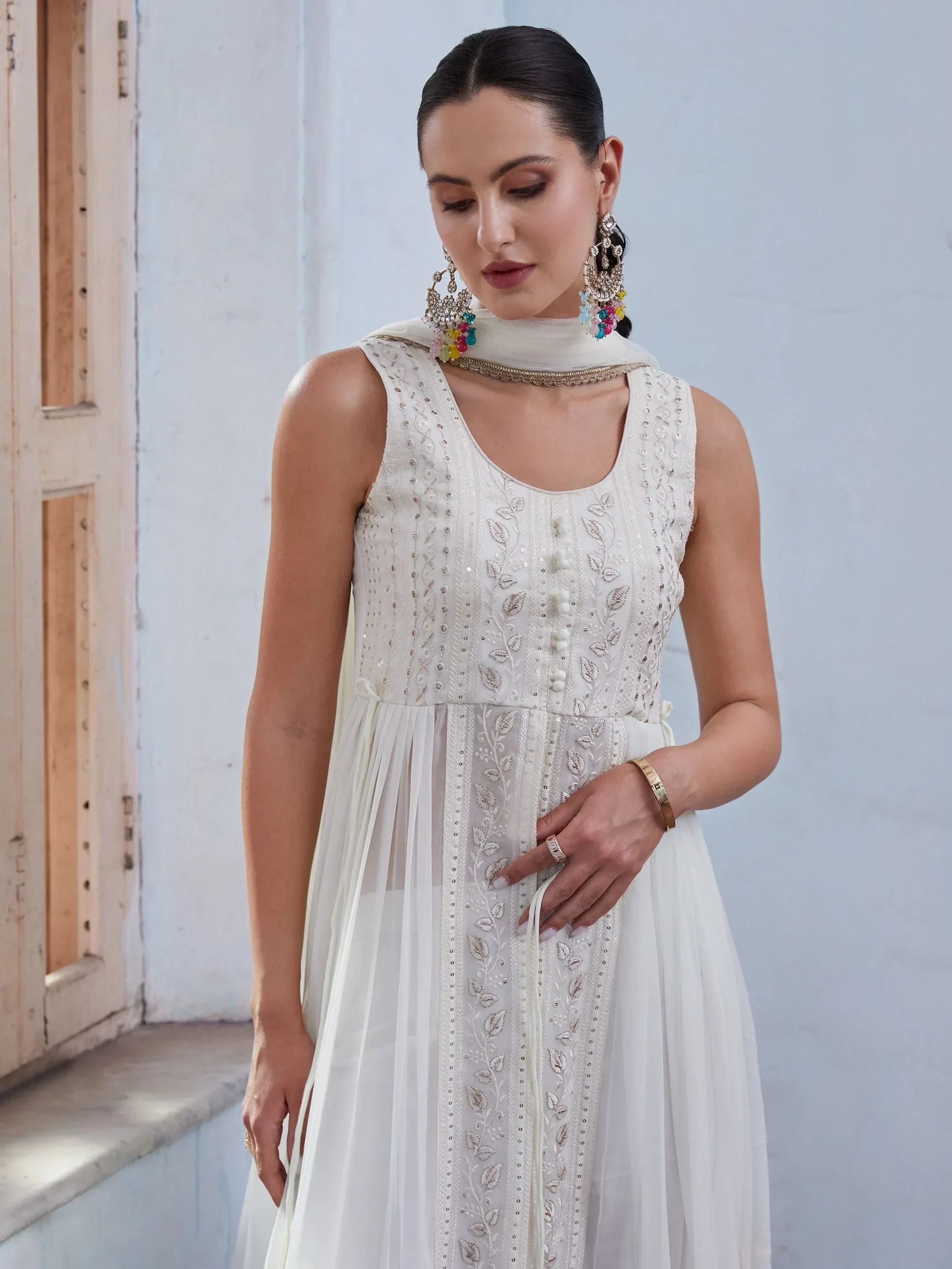 Woman in white embroidered Anarkali suit with sheer dupatta and statement earrings