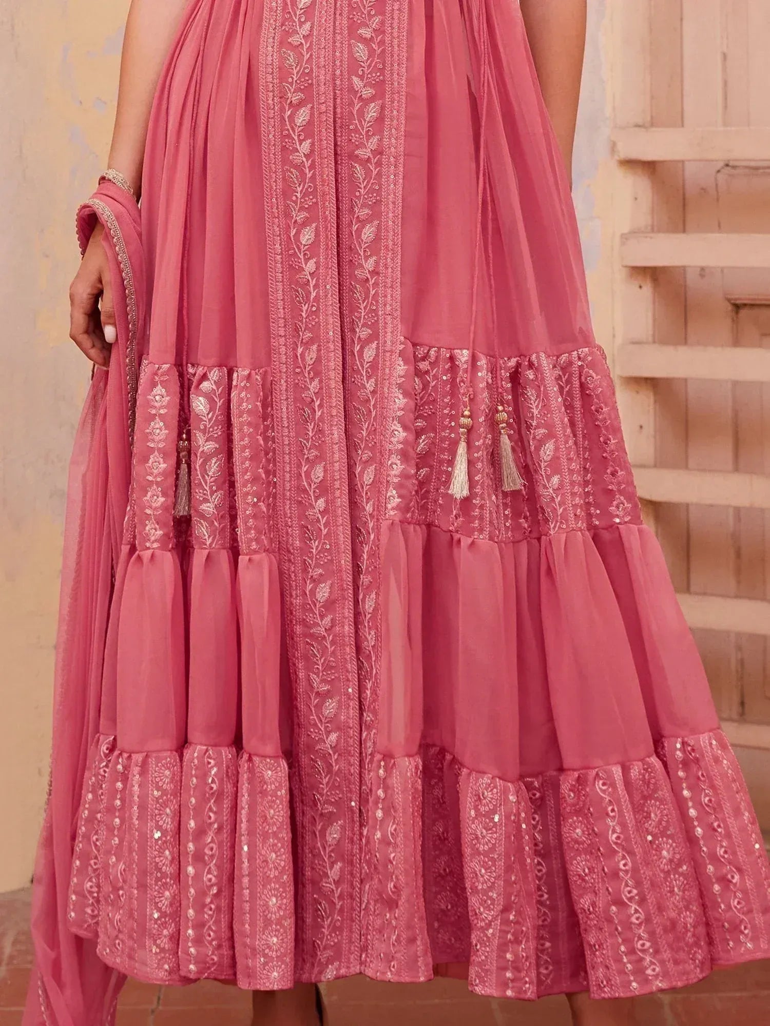 Pink embroidered ethnic gown with layered ruffles and tassels, perfect for Indian festive occasions