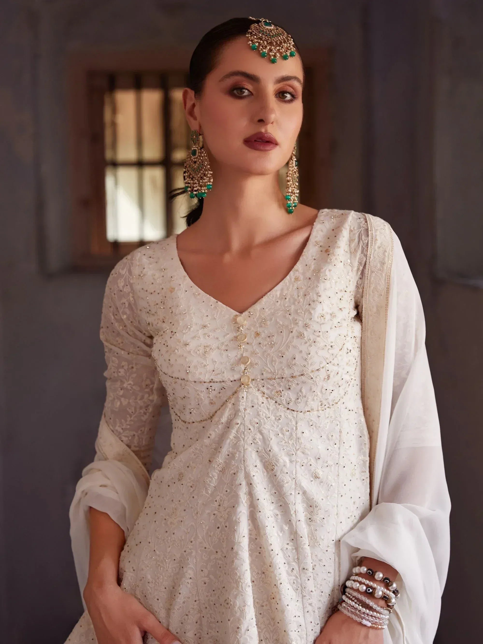 Woman in white embroidered ethnic gown with matching dupatta and statement jewelry