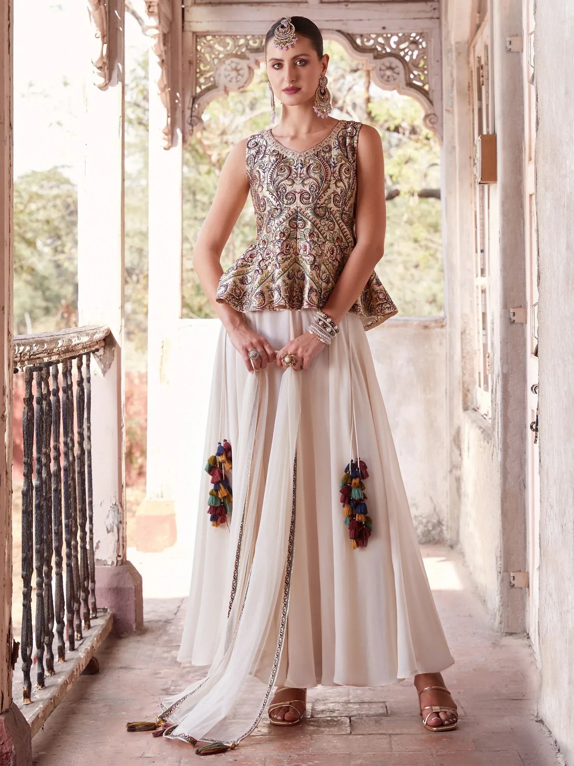 Woman wearing designer lehenga choli with embroidered peplum blouse and cream skirt