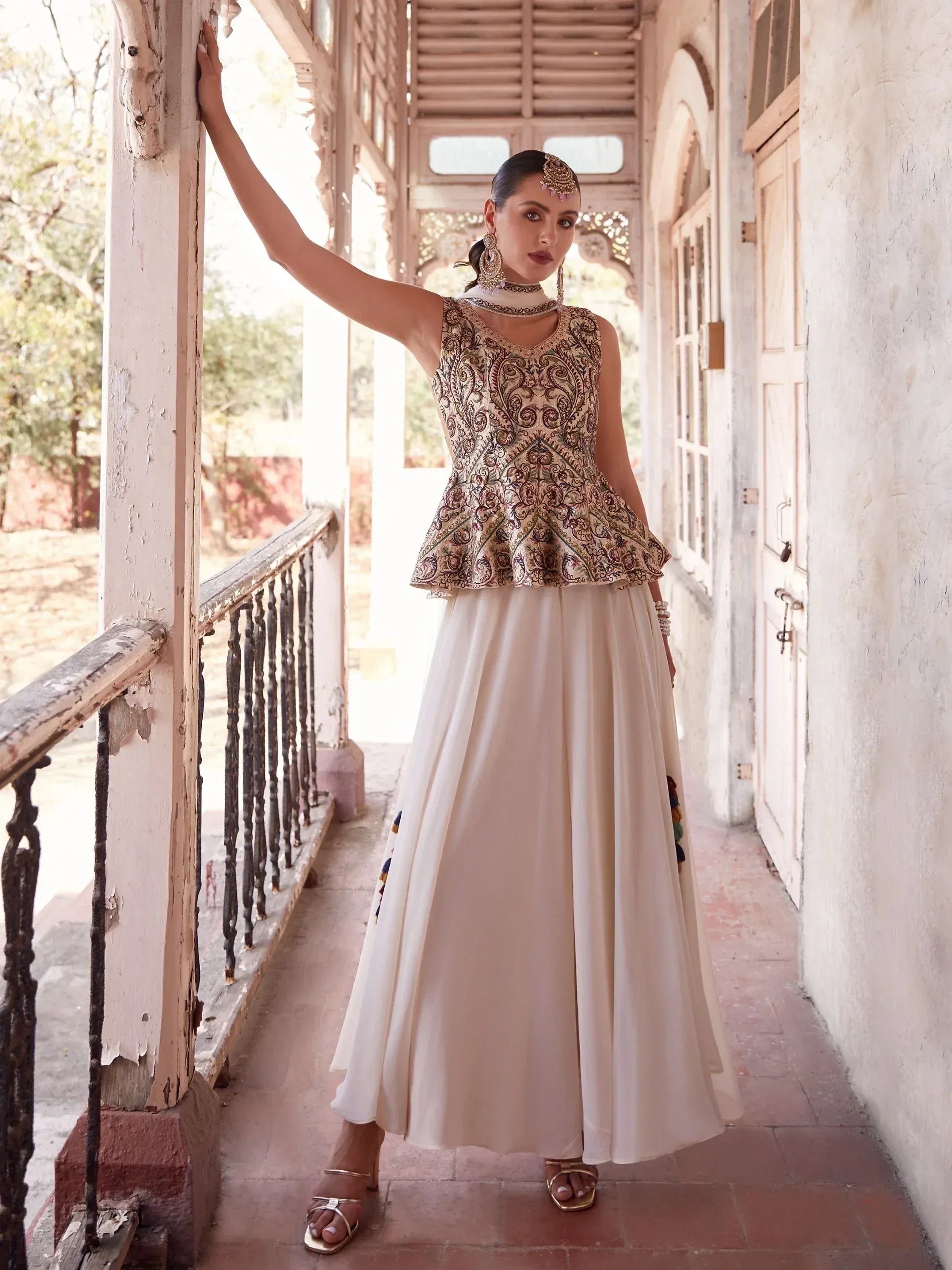 Woman in embroidered peplum top and cream flared skirt, Indian ethnic outfit, outdoor veranda