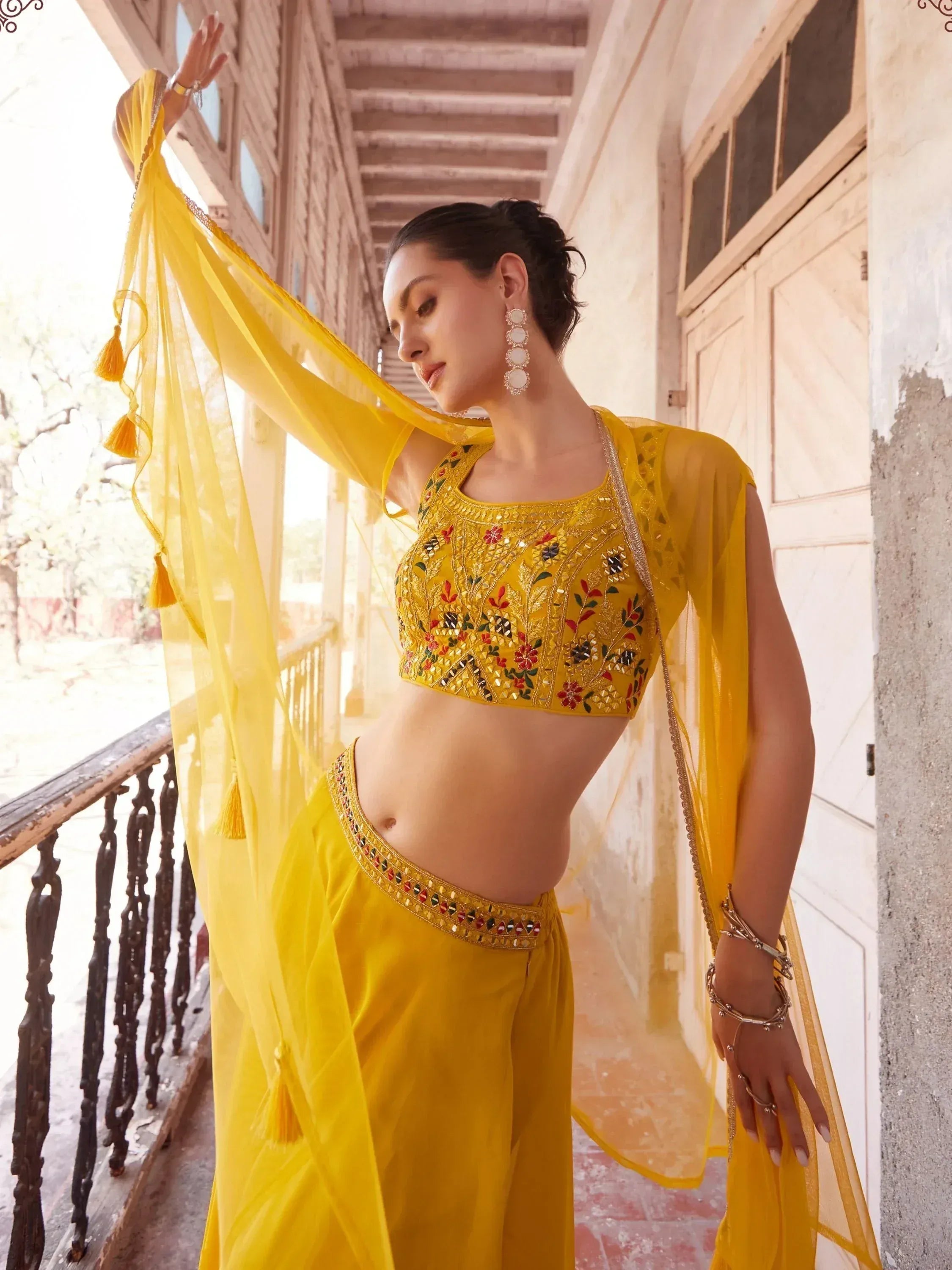 Woman in yellow embroidered lehenga choli with sheer dupatta, ethnic Indian wear