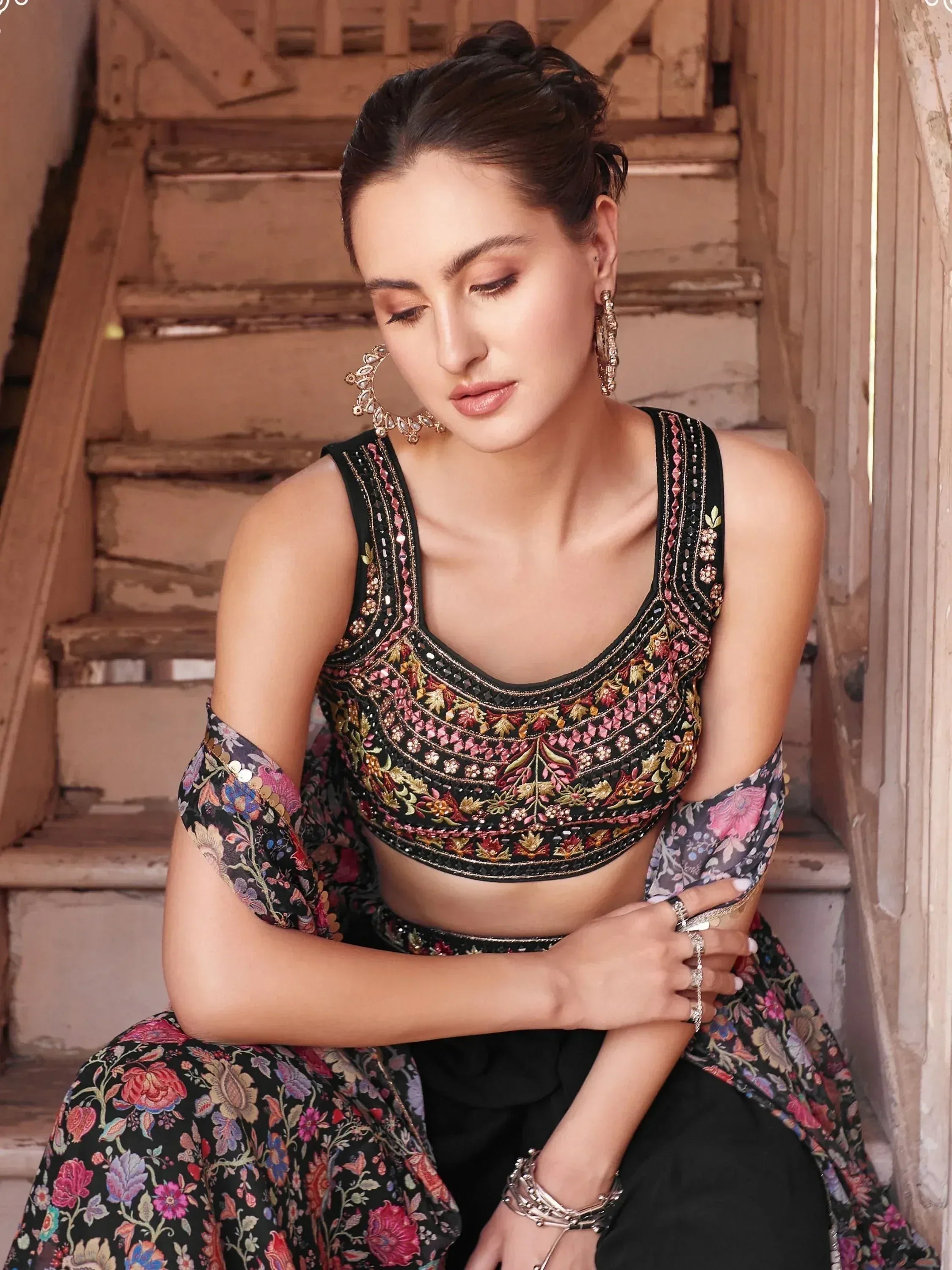 Woman in black floral embroidered lehenga choli with matching dupatta, wearing statement earrings.