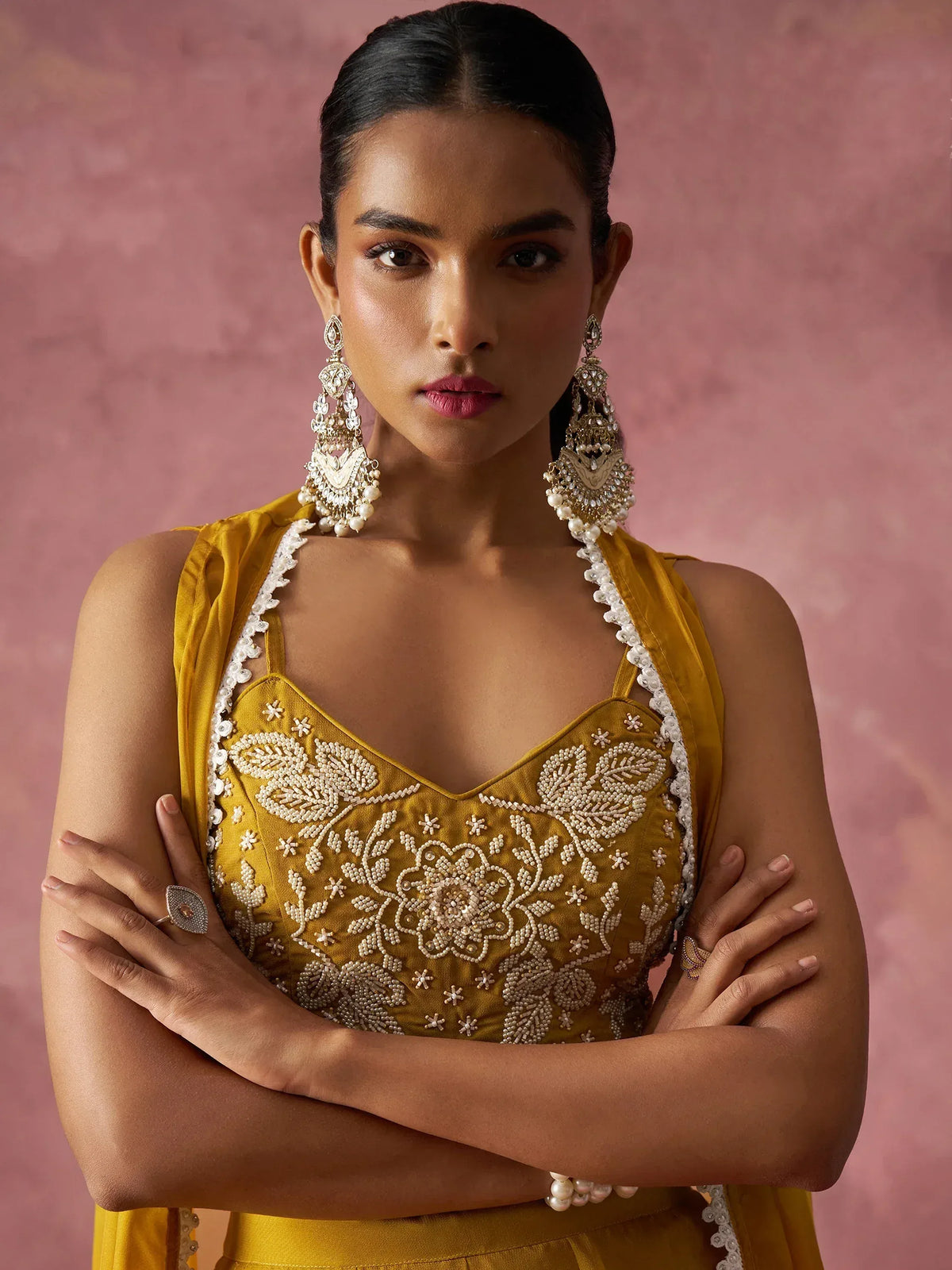 Mustard yellow embroidered ethnic gown with pearl detailing, paired with statement earrings for festive occasions.