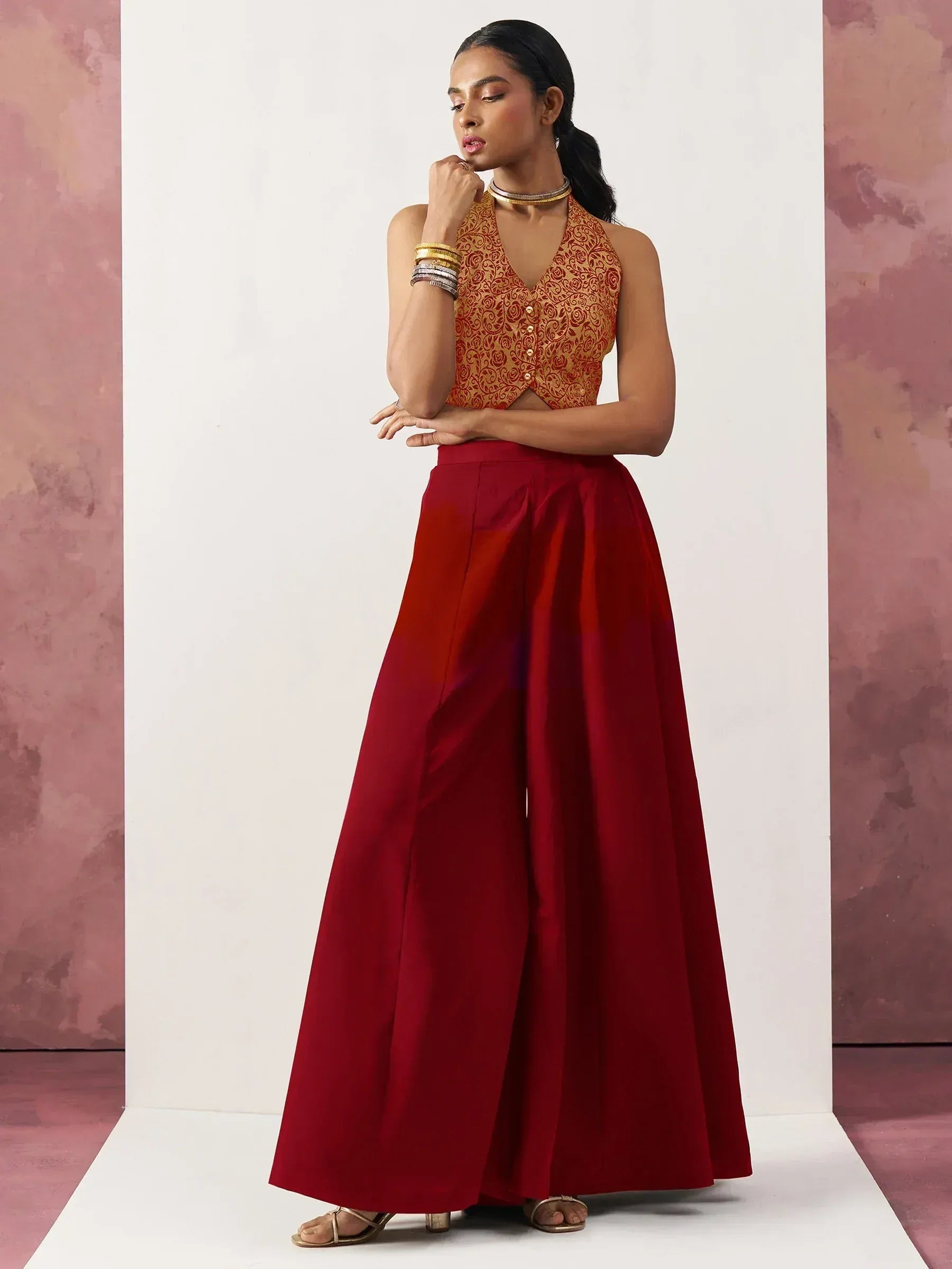Woman in red ethnic palazzo pants with gold embroidered halter top, styled for Indian occasions