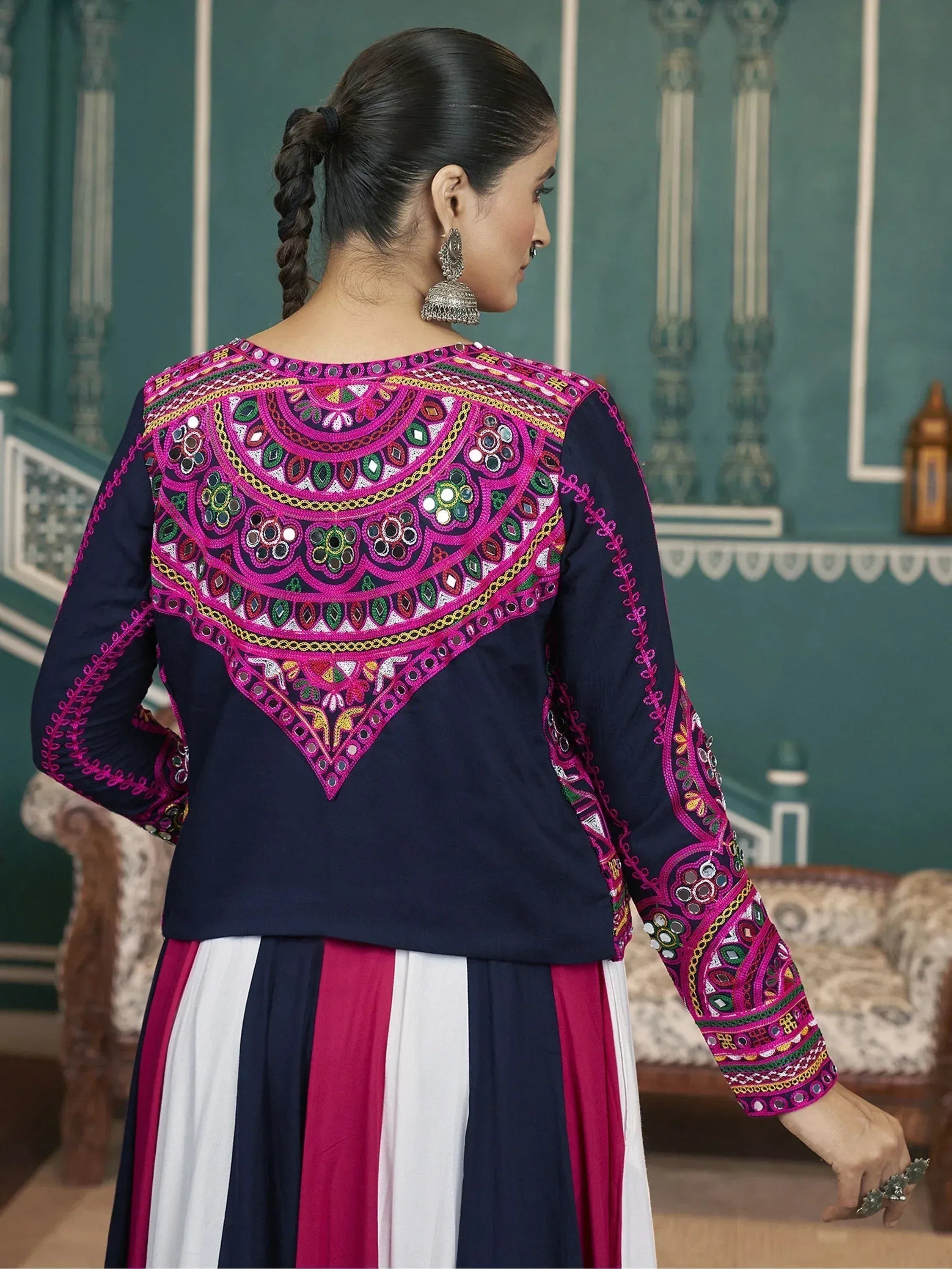 Navy blue ethnic kurti with vibrant pink mirror work embroidery, paired with striped skirt for festive occasions.
