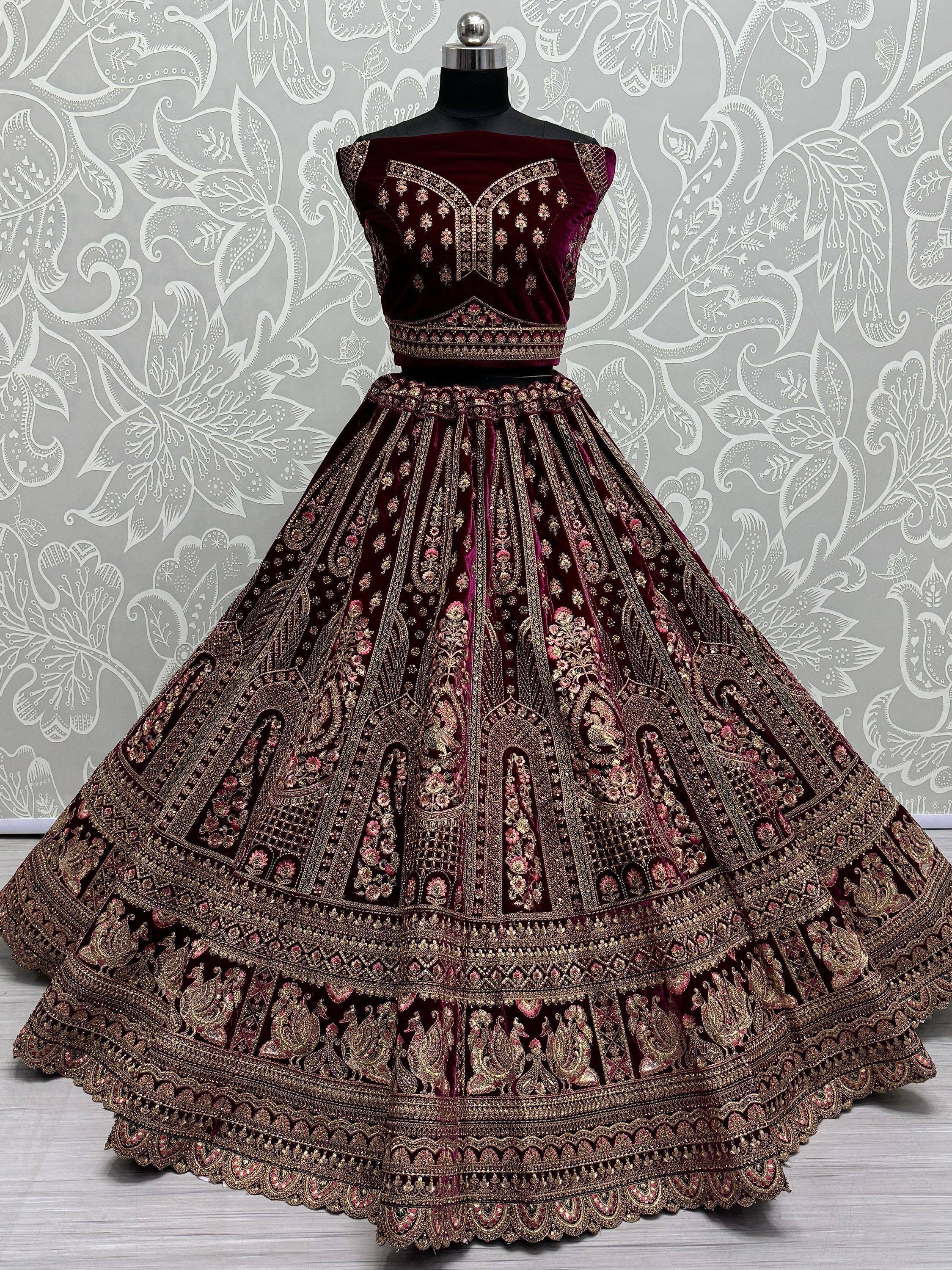 Luxury maroon velvet lehenga choli with heavy gold embroidery, perfect for Indian weddings and festive occasions.