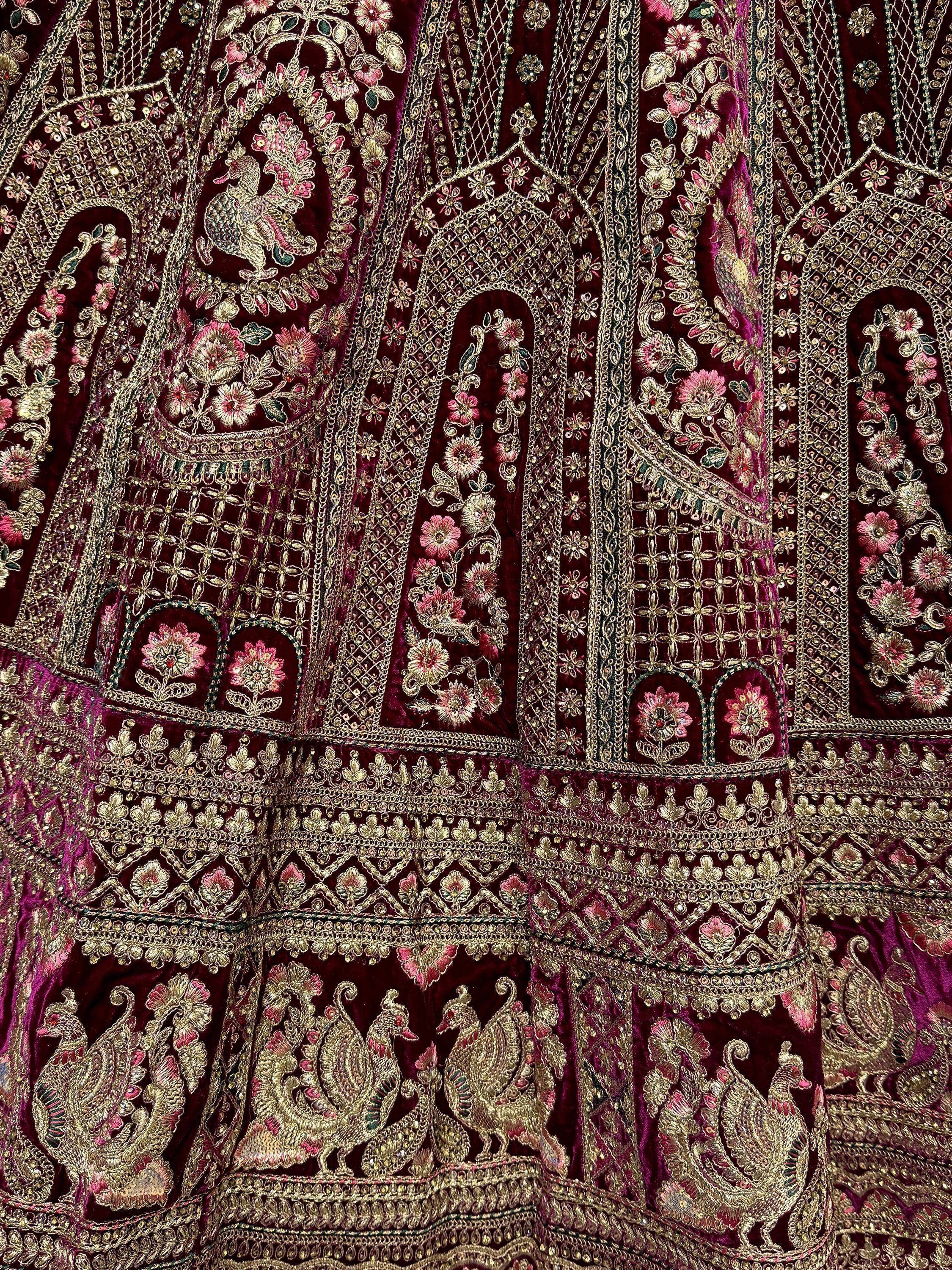 Luxury maroon velvet lehenga with intricate gold embroidery, floral motifs, and peacock designs for Indian ethnic wear.