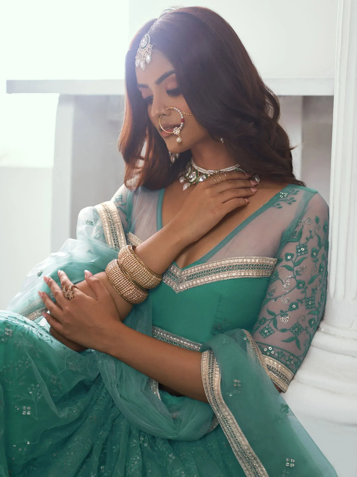 Elegant teal lehenga choli with sheer embroidered sleeves, perfect for Indian weddings and festive occasions.