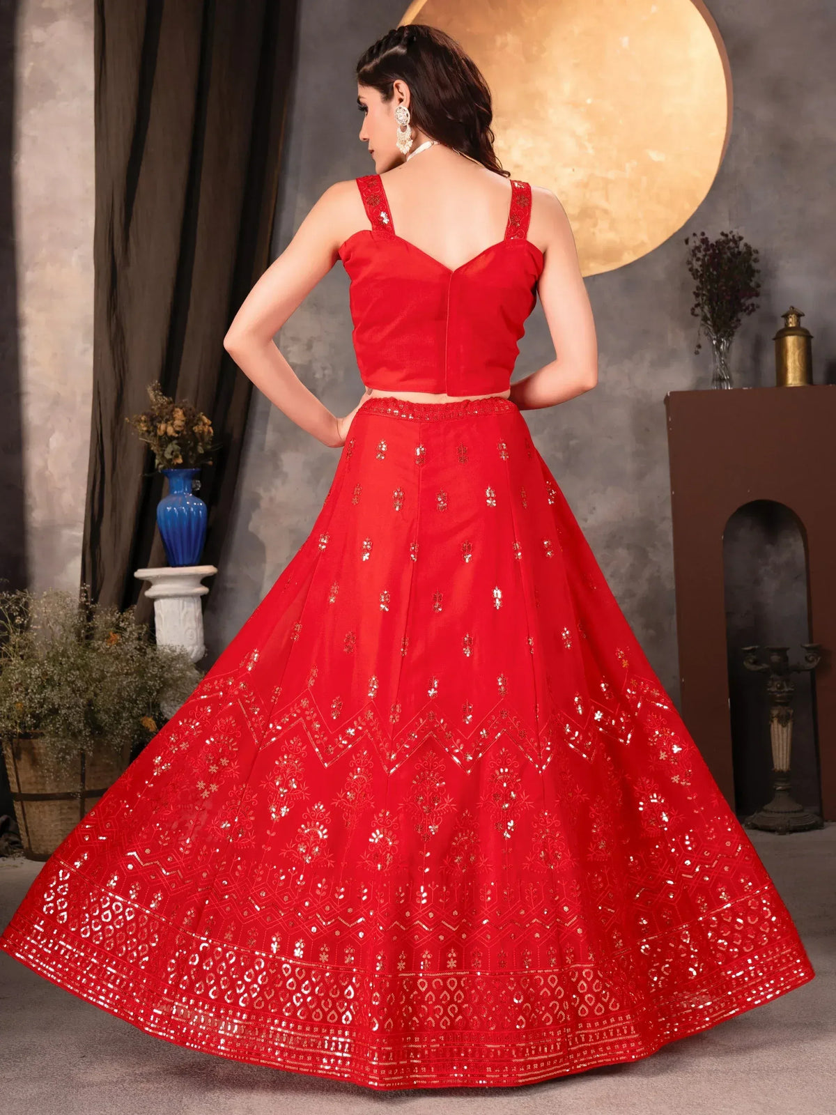 Red designer lehenga choli with intricate gold embroidery and mirror work, perfect for Indian ethnic occasions.