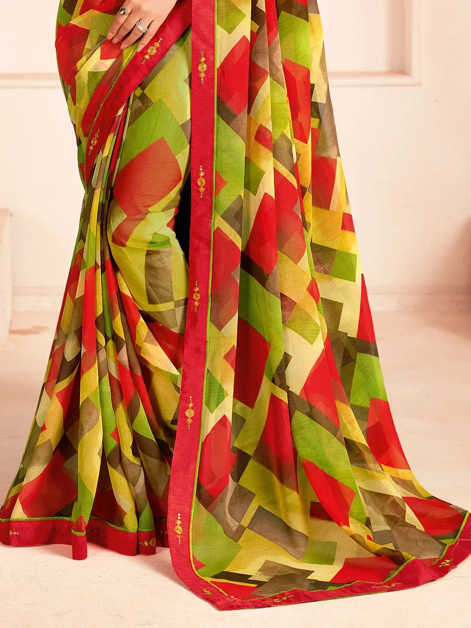 Vibrant geometric print saree with red border and gold embellishments, perfect for ethnic occasions.