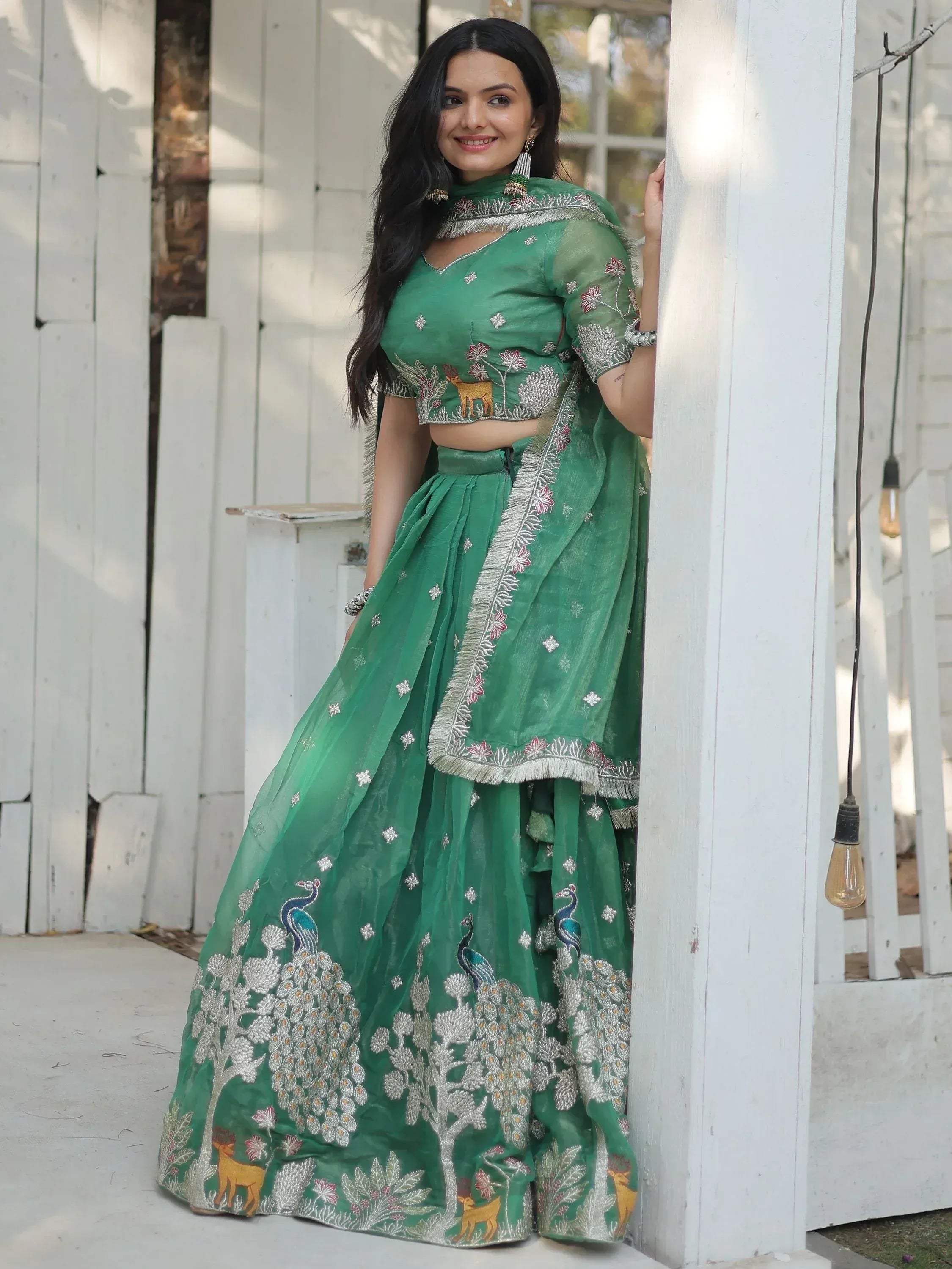 Green embroidered lehenga choli with peacock and deer motifs, perfect for Indian ethnic wear occasions.