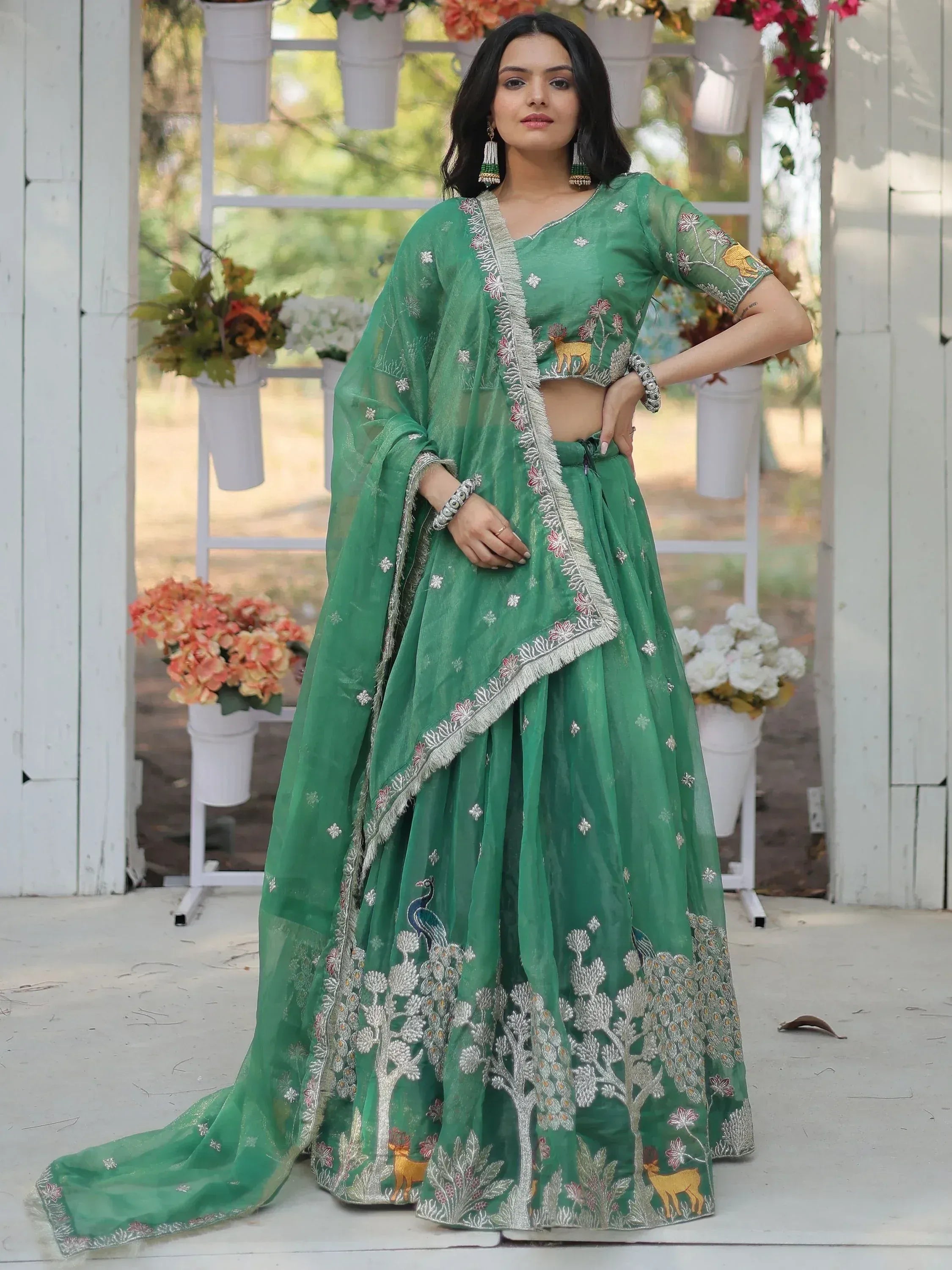 Green embroidered lehenga choli with peacock and deer motifs, perfect for Indian ethnic wear occasions.