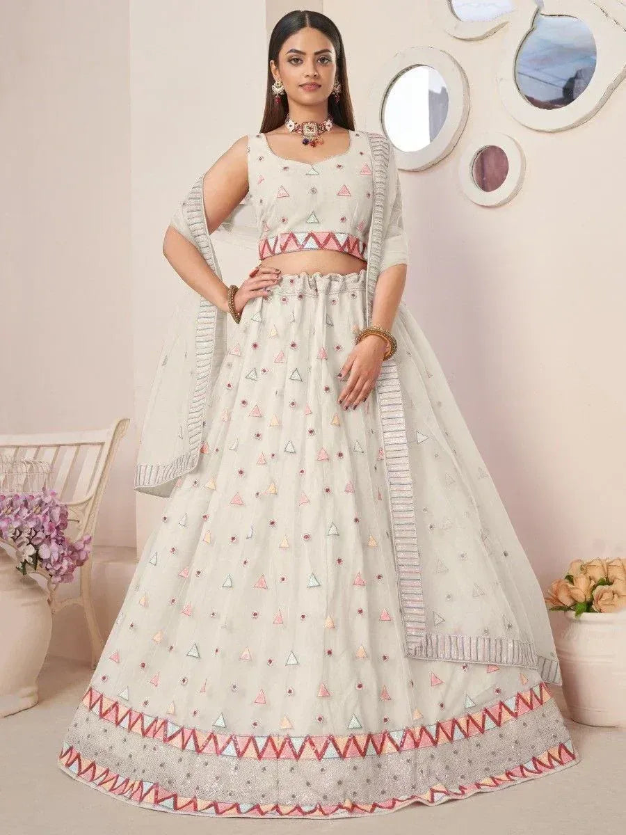 White embroidered lehenga choli with geometric triangle patterns and colorful border, perfect for Indian ethnic occasions.