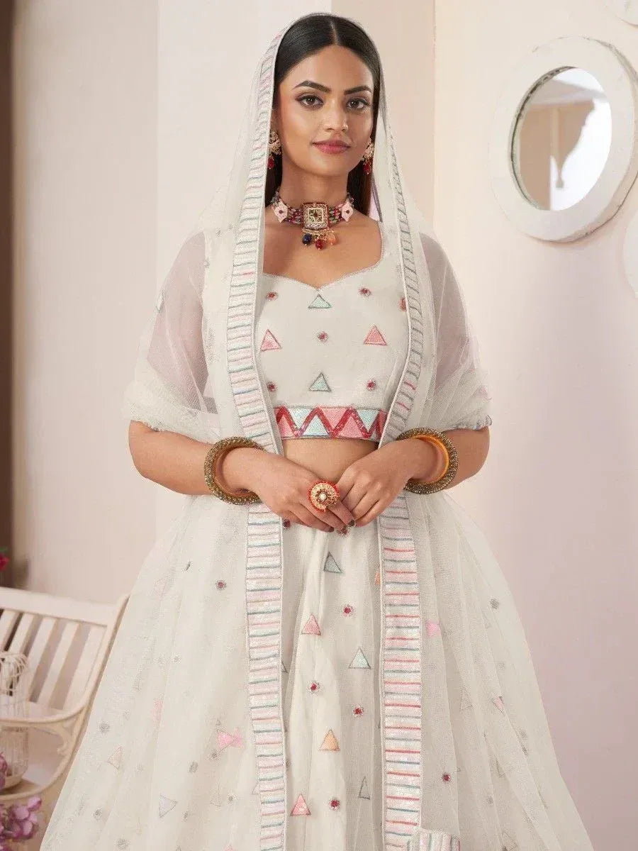 White embroidered lehenga choli with geometric patterns and sheer dupatta, styled for ethnic occasions