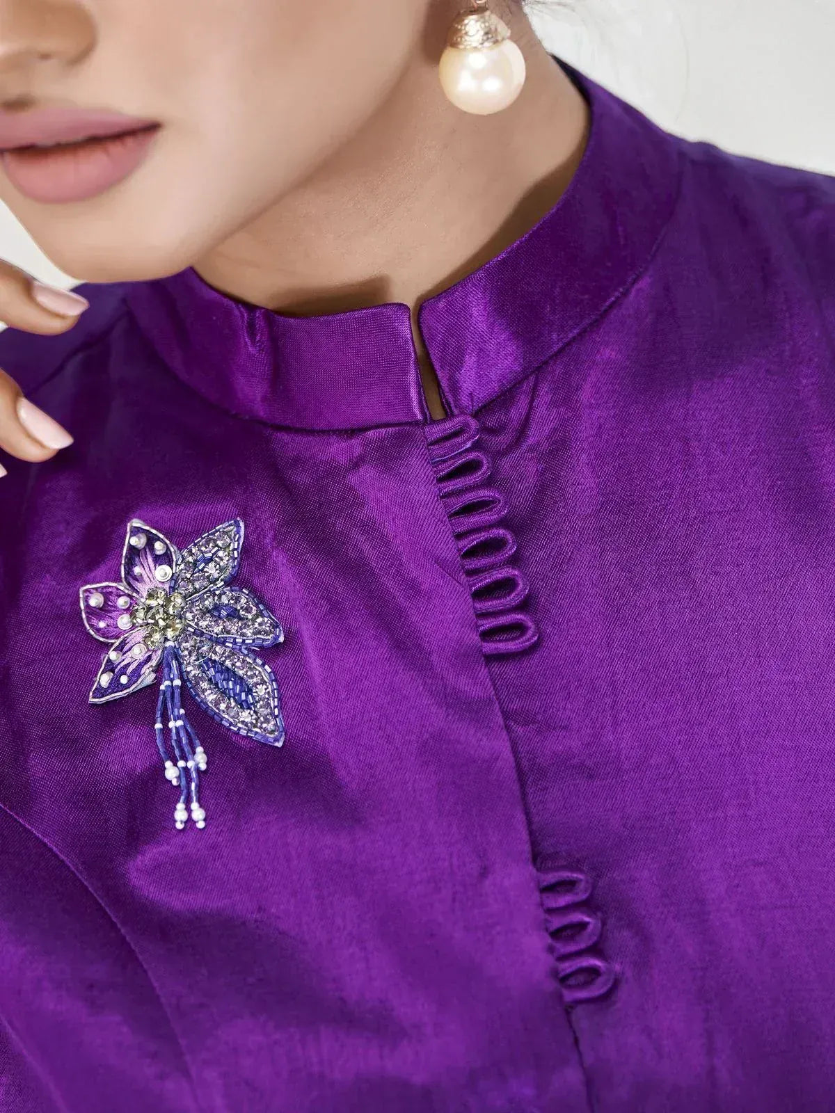 Purple ethnic gown with floral embellishment and pearl earrings