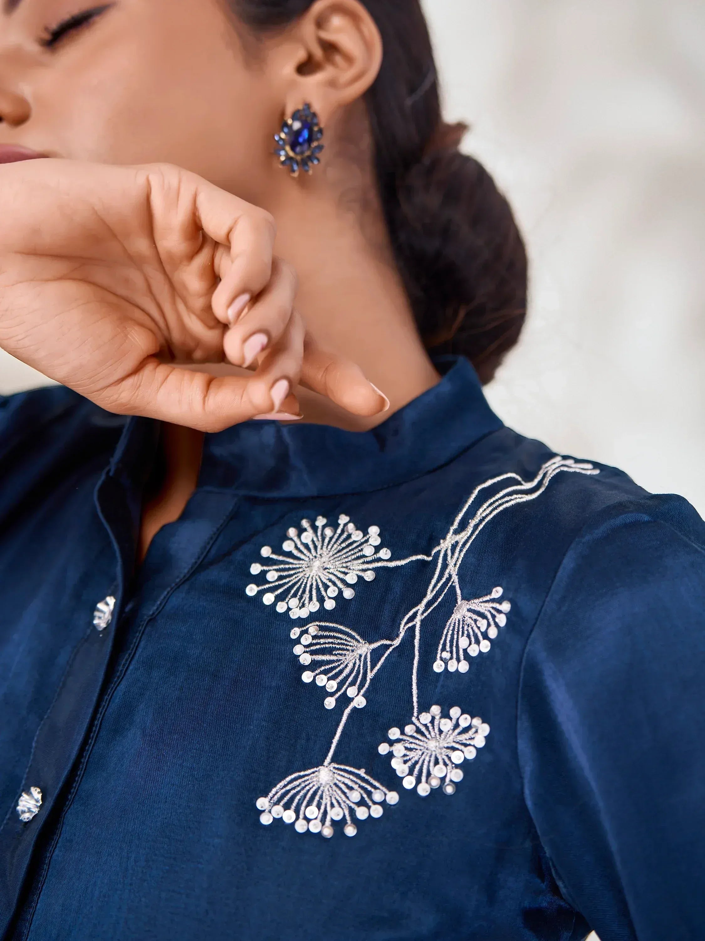 Navy blue ethnic blouse with intricate white floral embroidery and matching earrings
