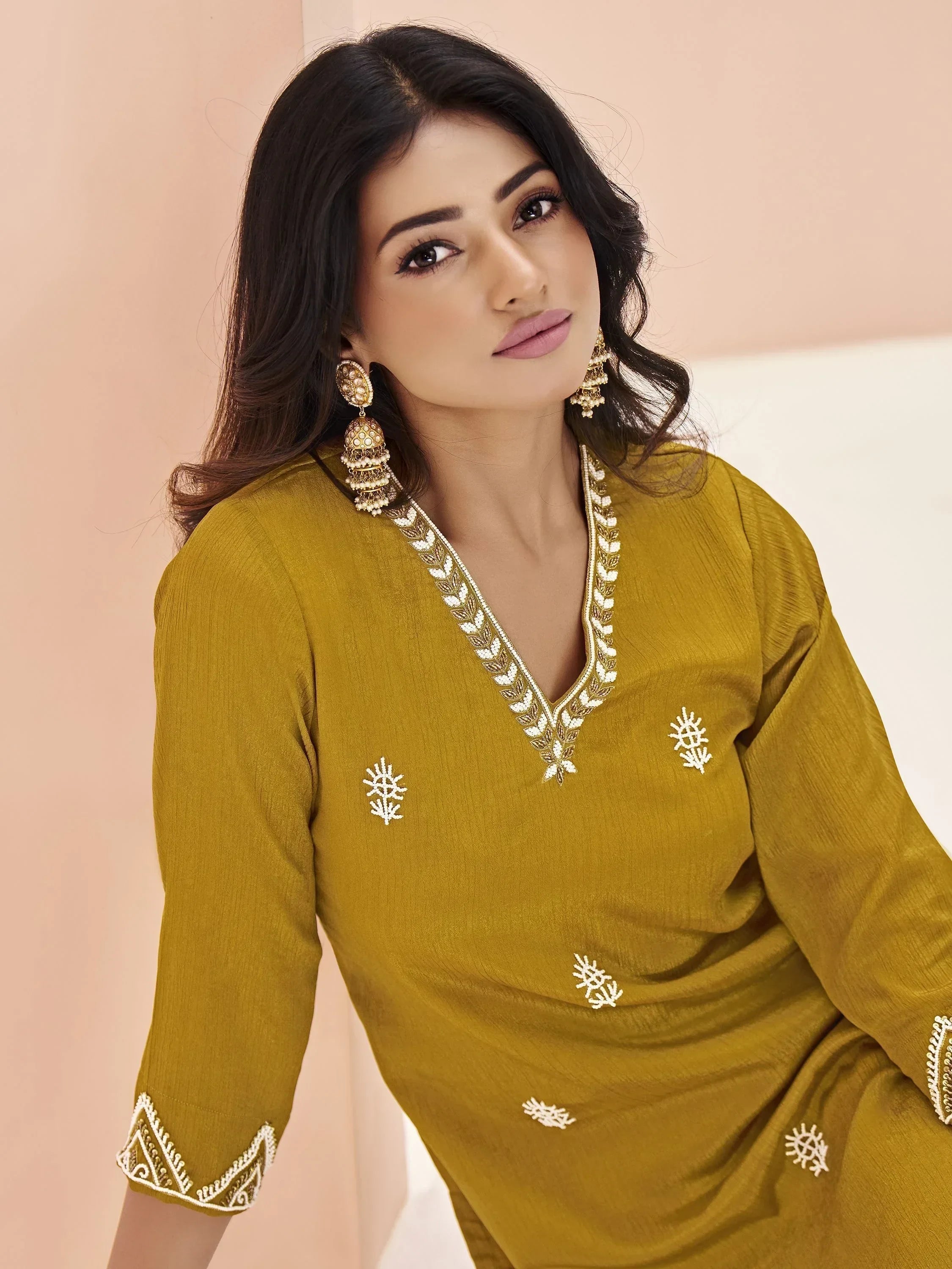 Woman in mustard yellow embroidered salwar kameez with statement earrings