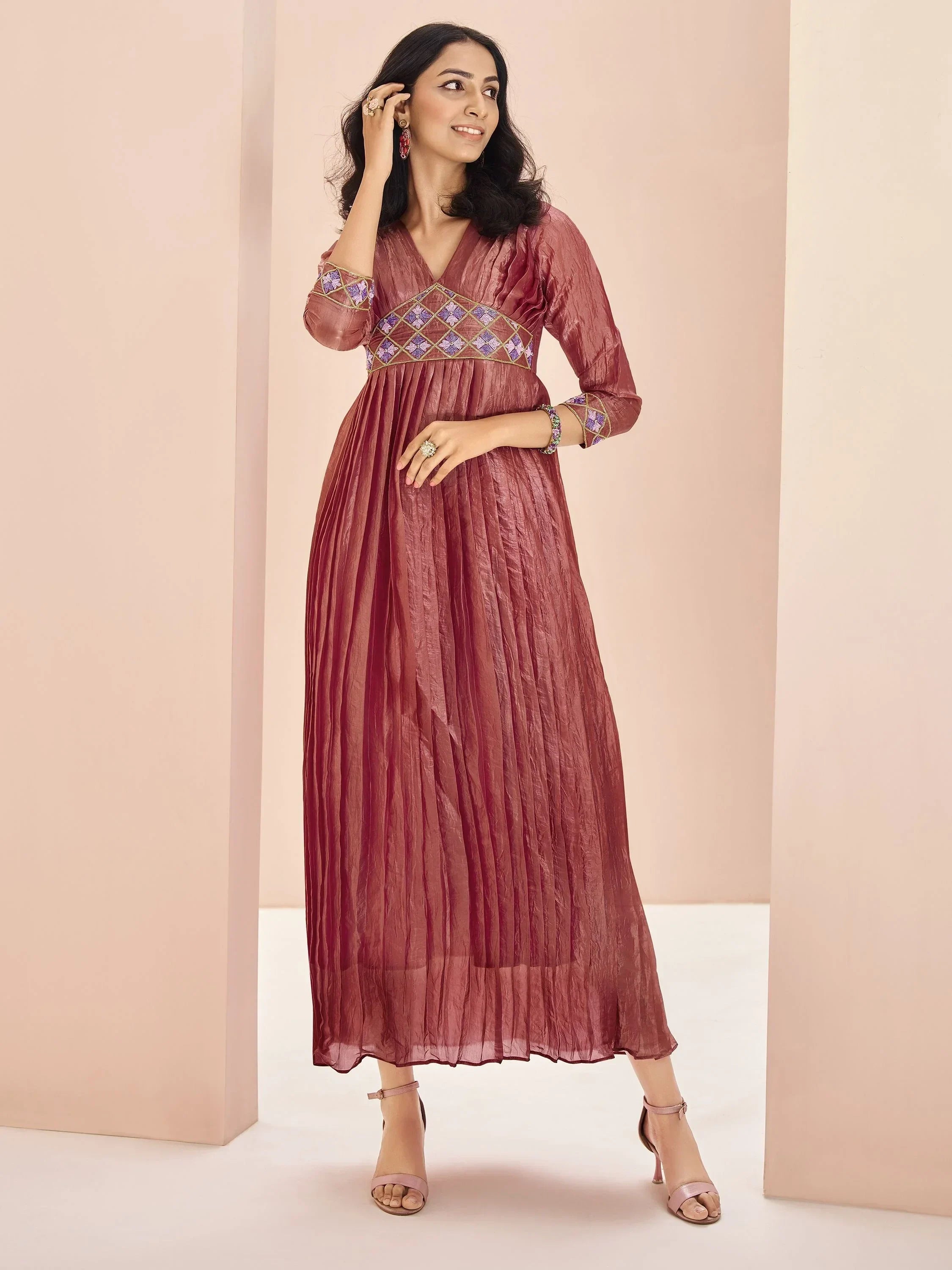 Woman wearing a maroon pleated ethnic gown with embroidered waist and three-quarter sleeves