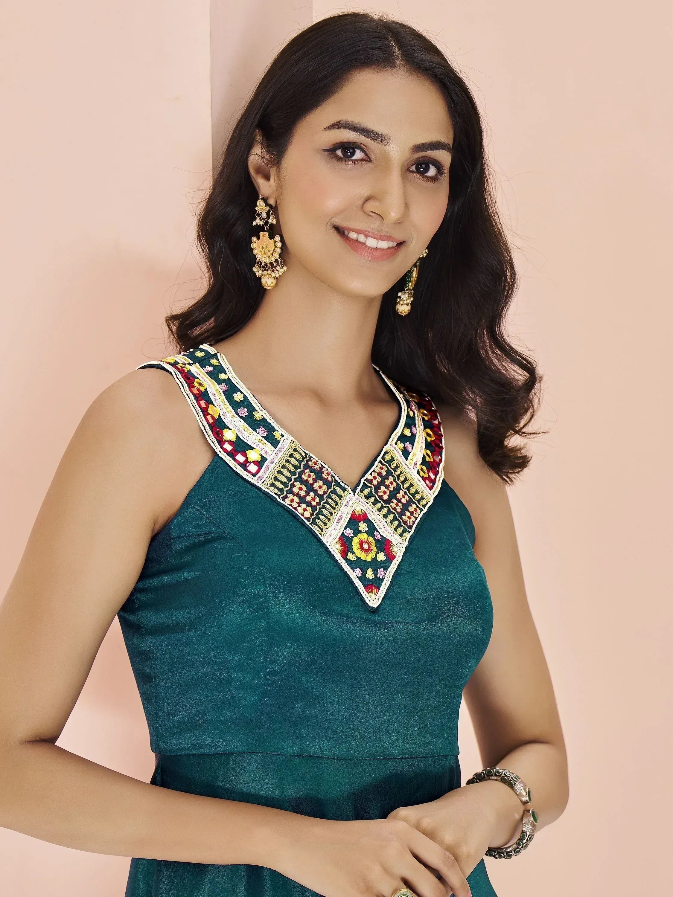 Woman in green ethnic gown with colorful floral embroidery and gold jewelry