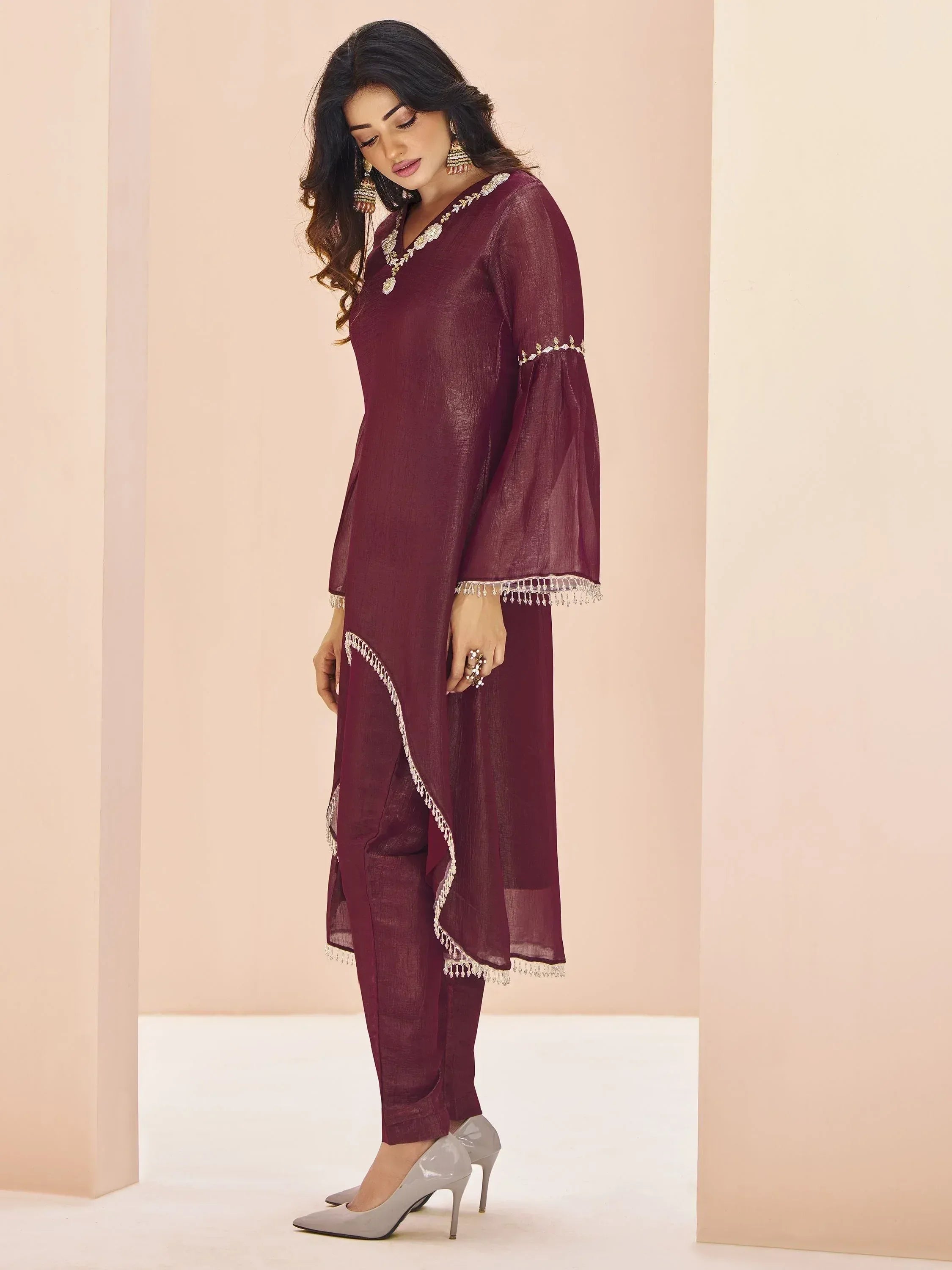 Maroon ethnic salwar kameez with gold embroidery and tassels, styled with heels for festive occasions