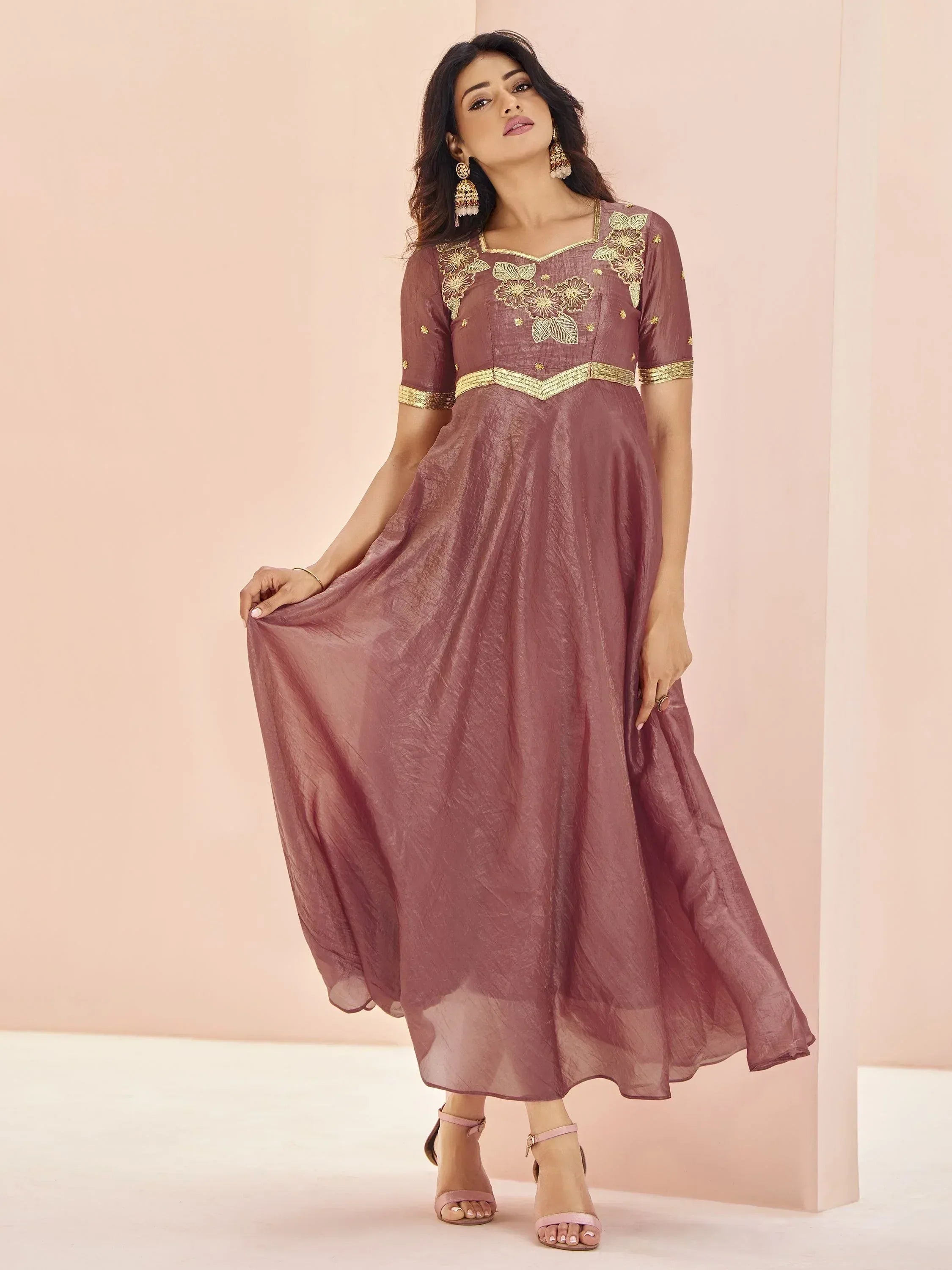 Mauve ethnic gown with gold floral embroidery and waistband, styled with jhumka earrings for festive occasions