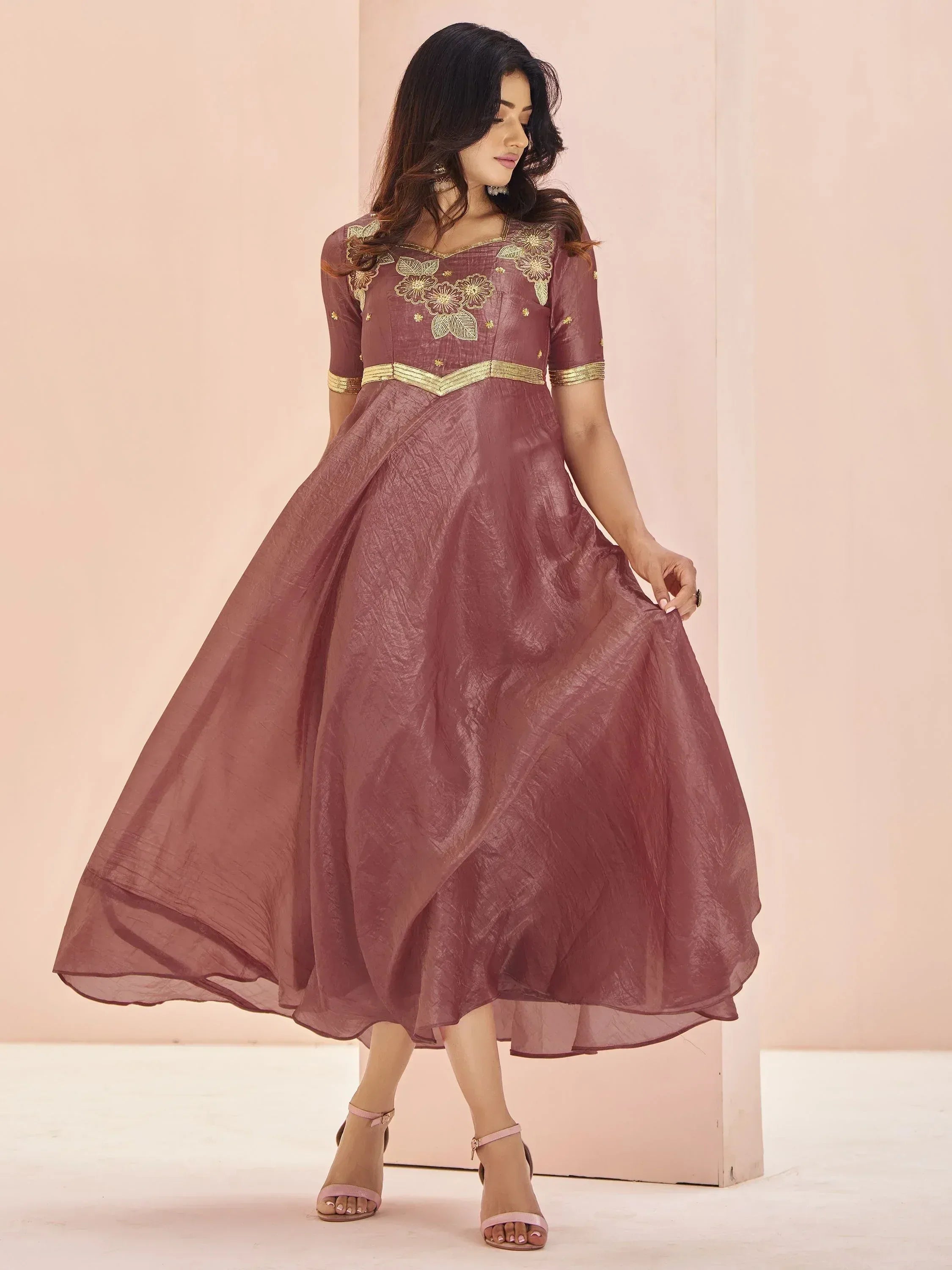 Elegant maroon ethnic gown with gold floral embroidery and flared skirt, perfect for Indian occasions.