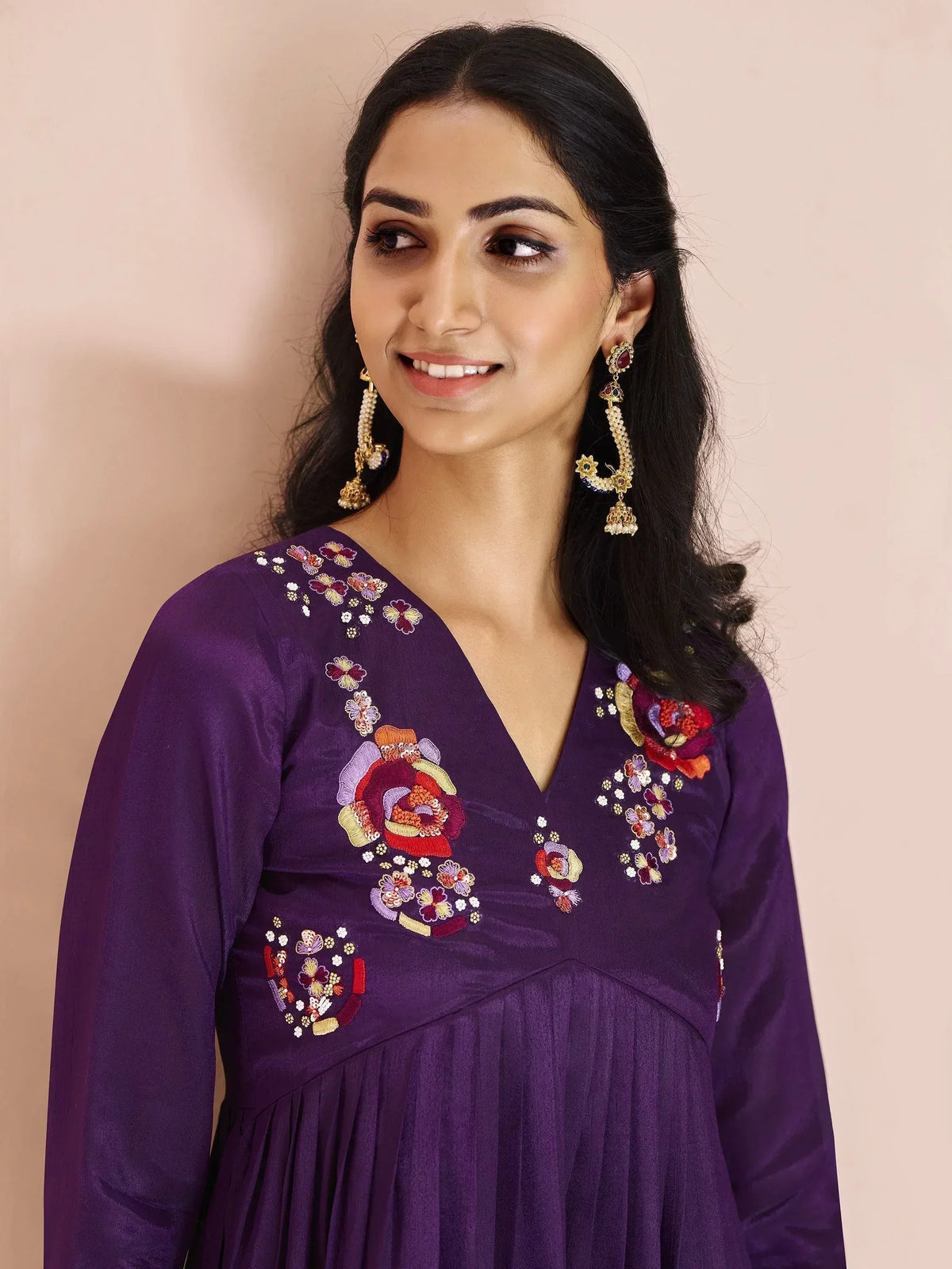 Purple ethnic gown with floral embroidery and jhumka earrings, perfect for Indian occasions