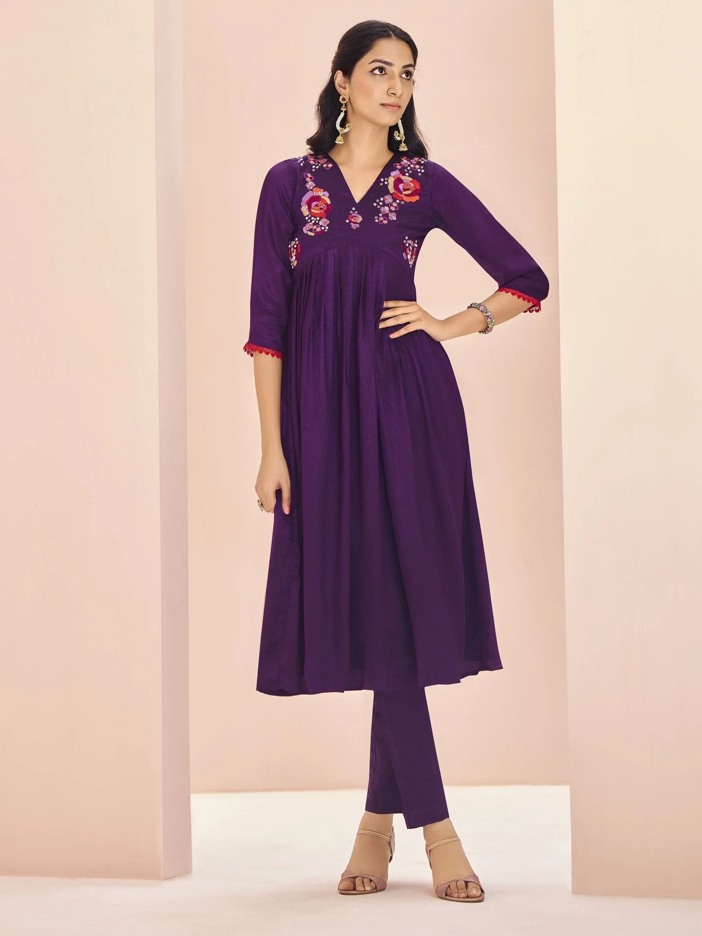Woman wearing purple embroidered ethnic kurti with matching pants and elegant earrings