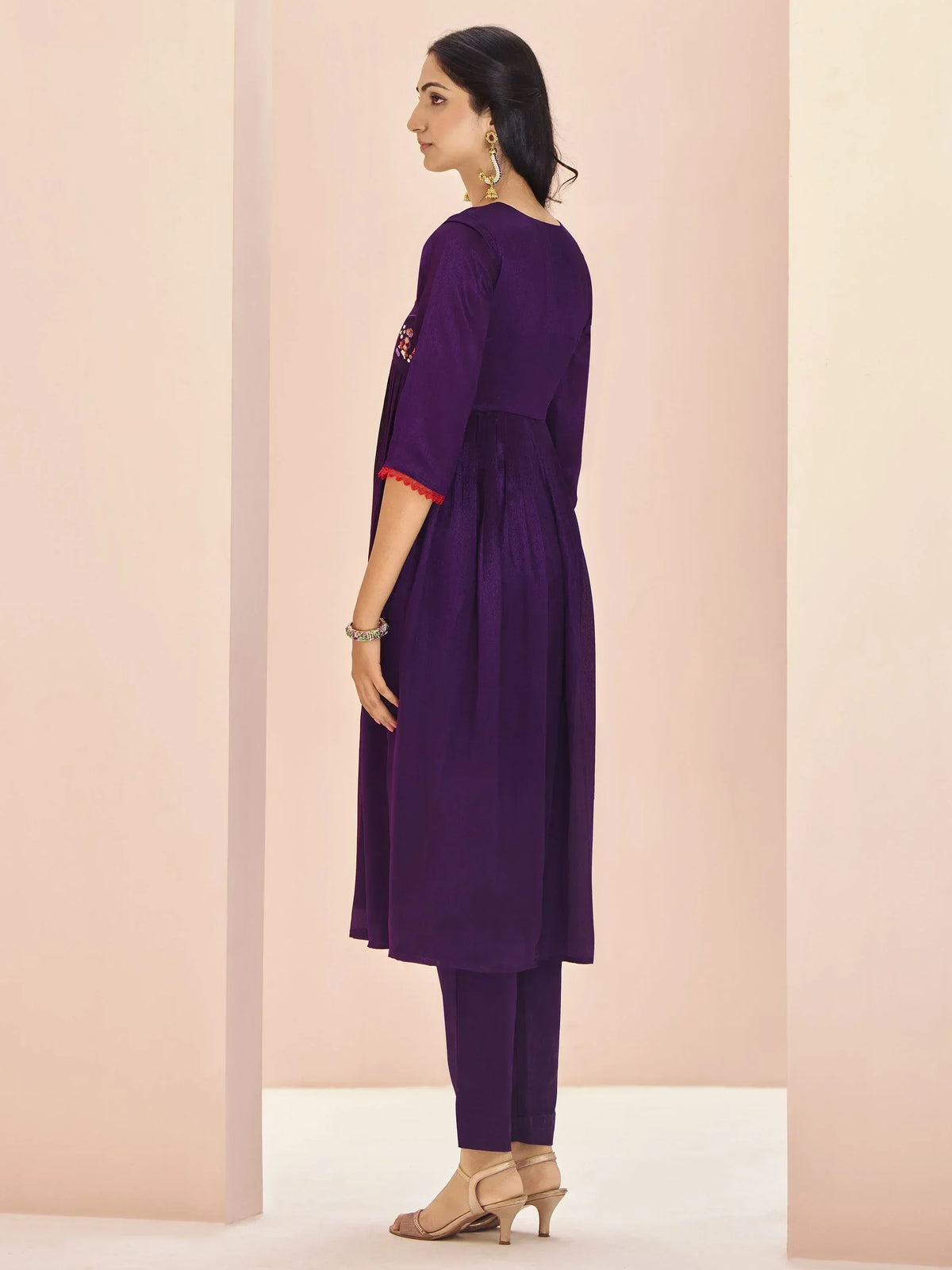 Purple ethnic kurta with red trim and matching pants, styled with gold earrings and heels
