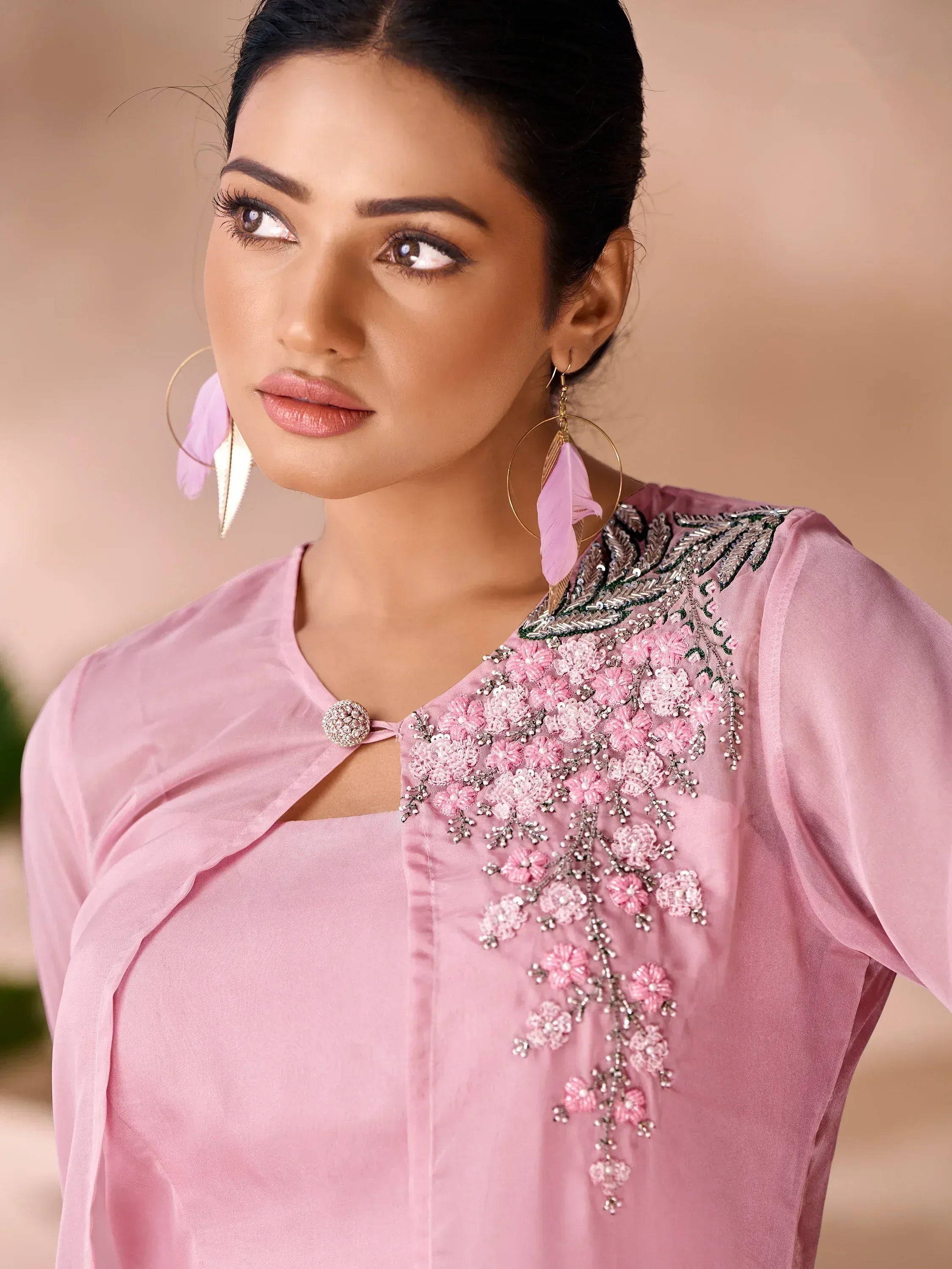 Pink embroidered ethnic kurti with floral detailing and feather earrings, perfect for Indian festive wear.