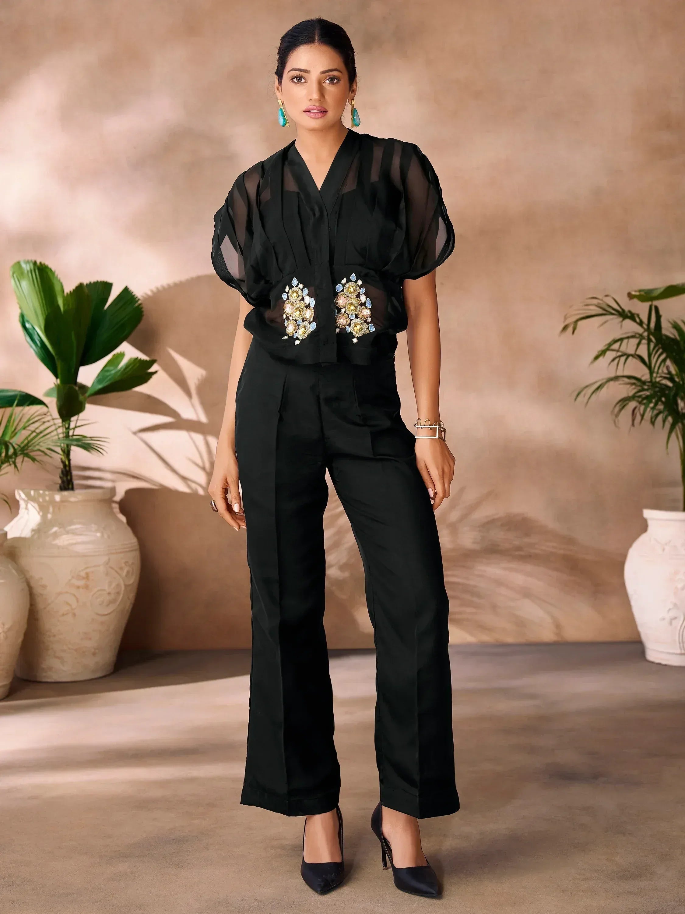 Black ethnic pantsuit with sheer puff sleeves and floral embroidery, paired with heels and statement earrings.