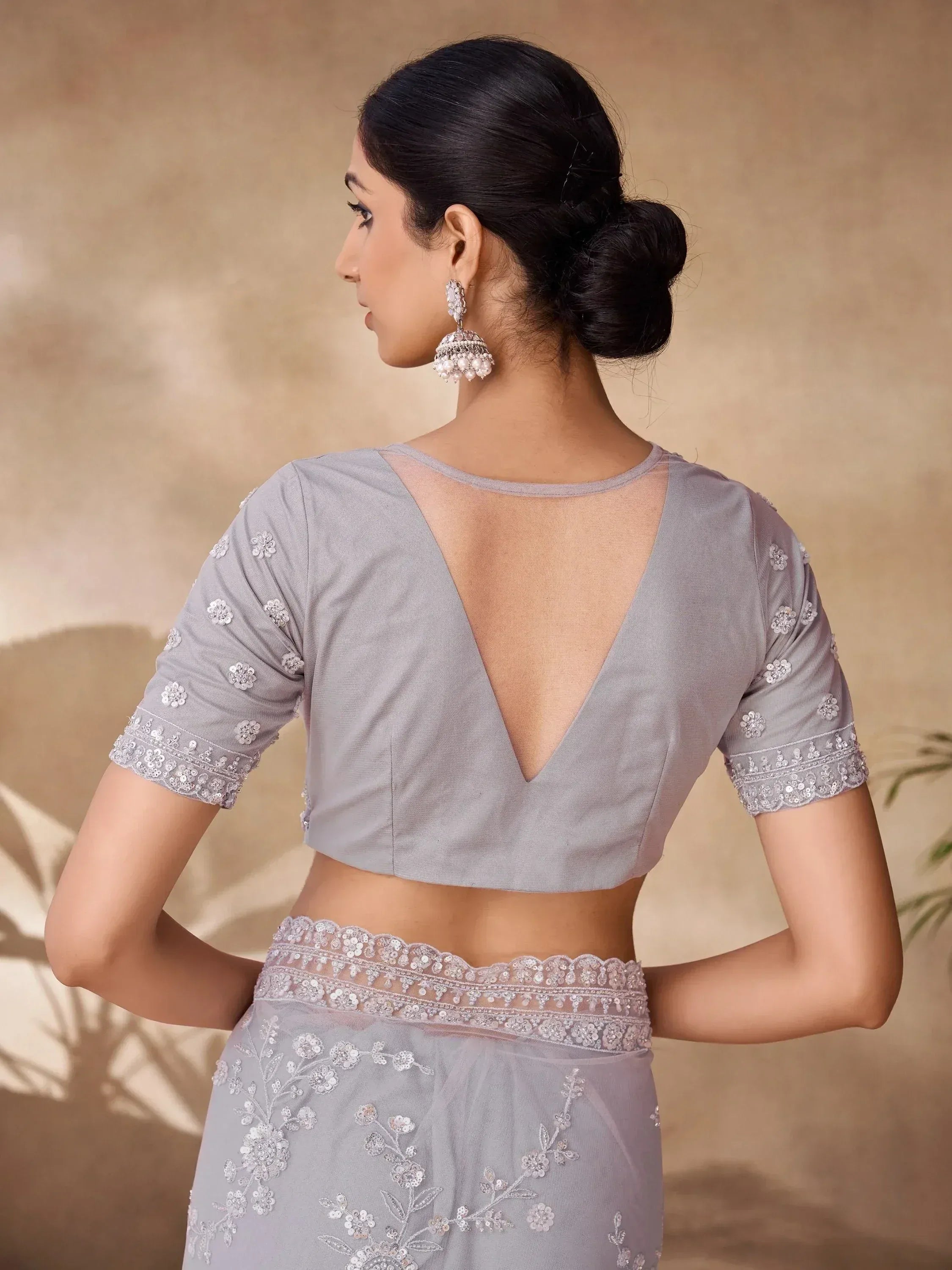 Grey embroidered saree with backless blouse, floral detailing, and pearl jhumka earrings for ethnic wear