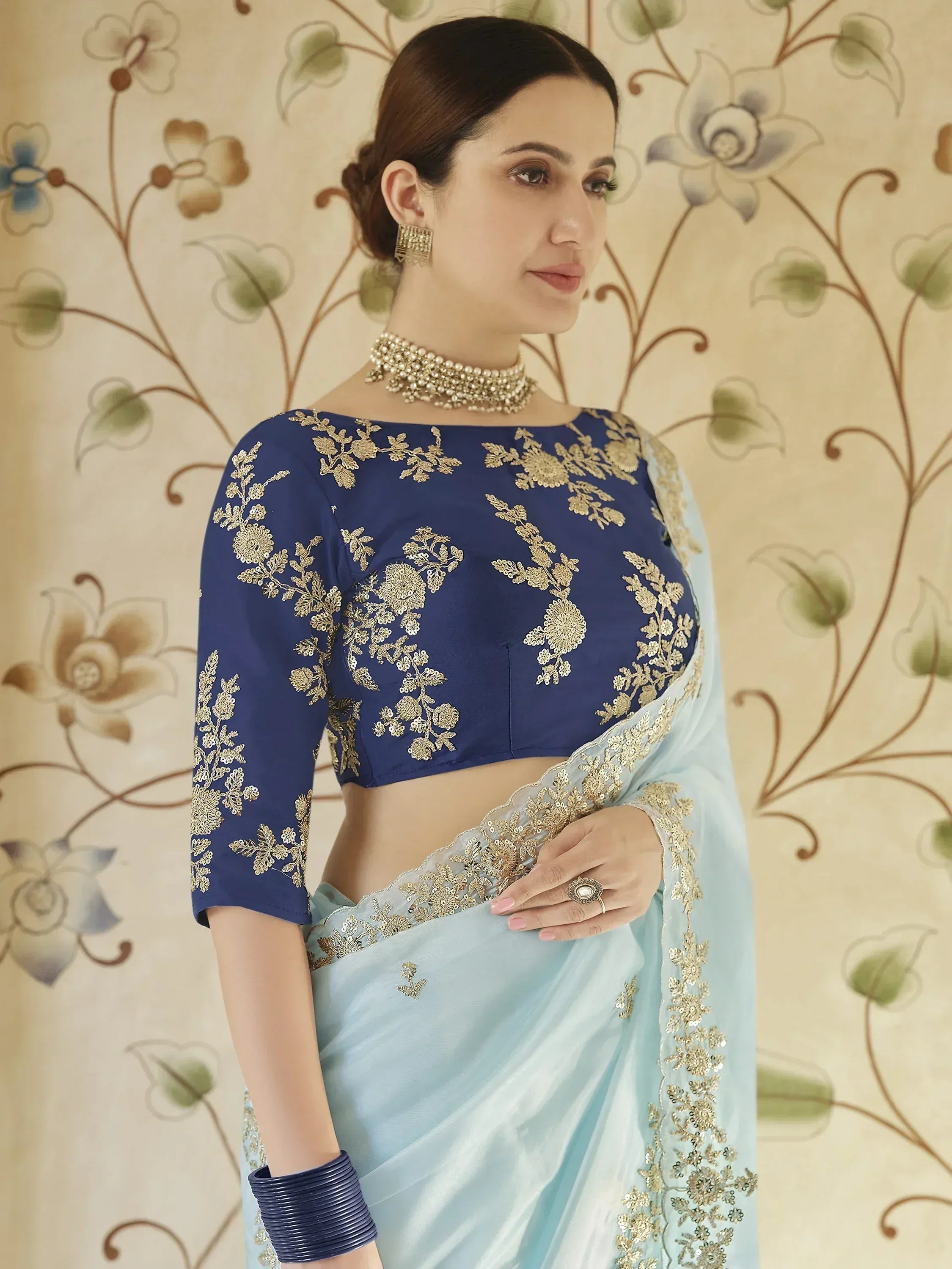 Blue embroidered saree with gold floral work, paired with matching blouse for Indian ethnic wear