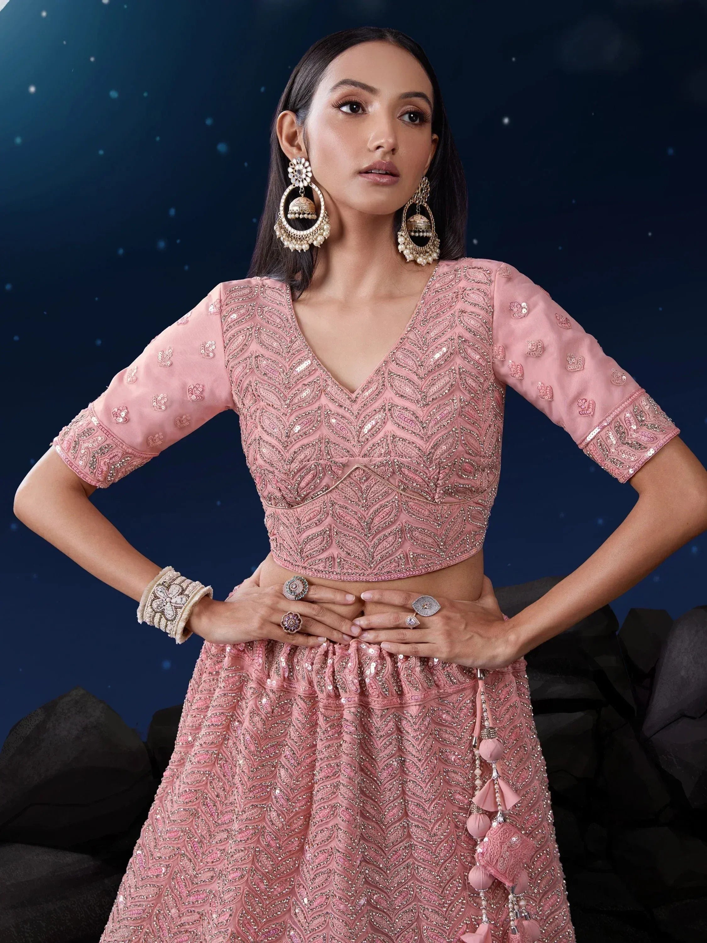 Pink embroidered lehenga choli with sequin work, jhumka earrings, and statement rings for Indian ethnic wear