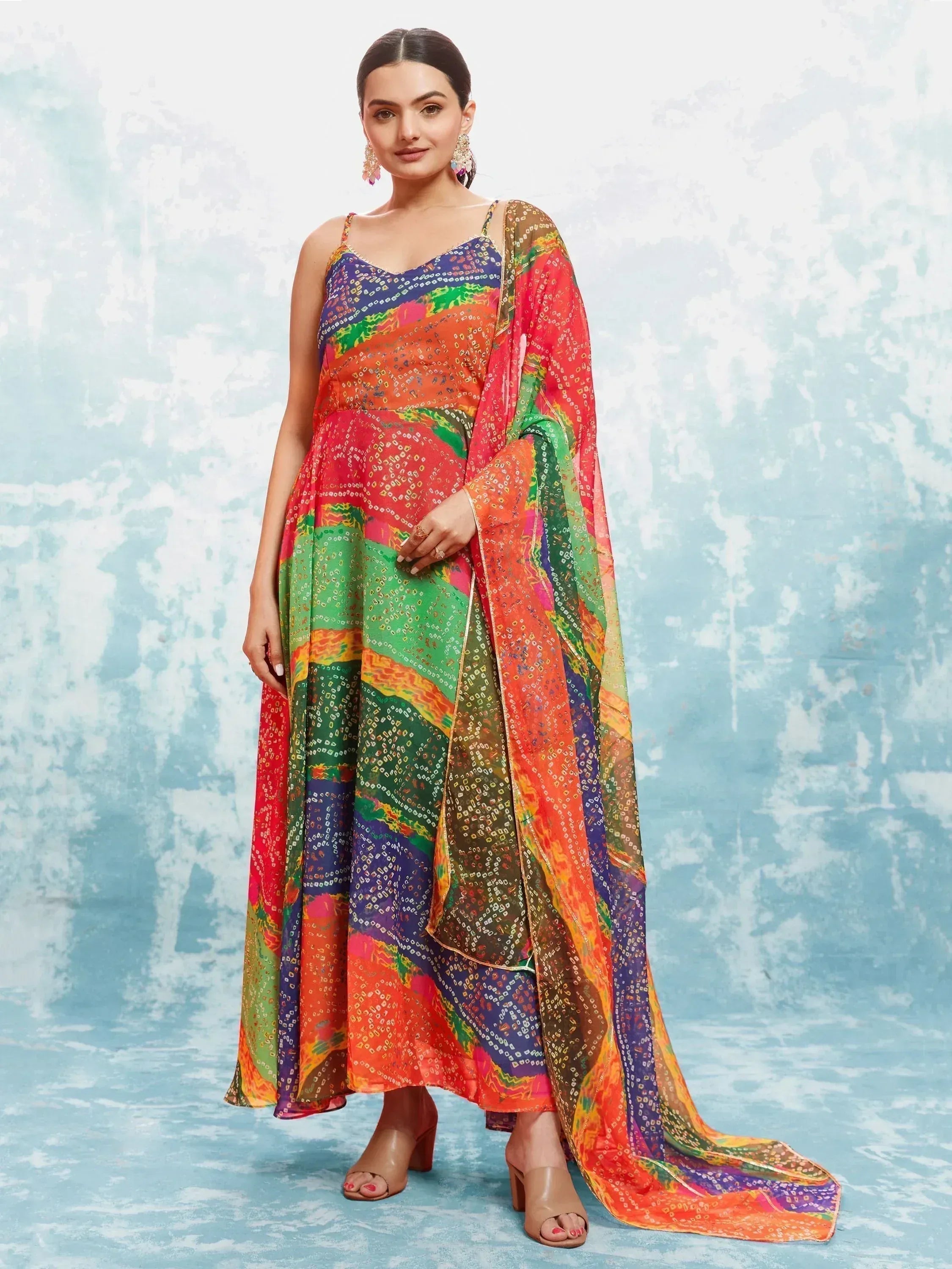 Woman in a colorful printed ethnic gown with matching dupatta, posing on a light background