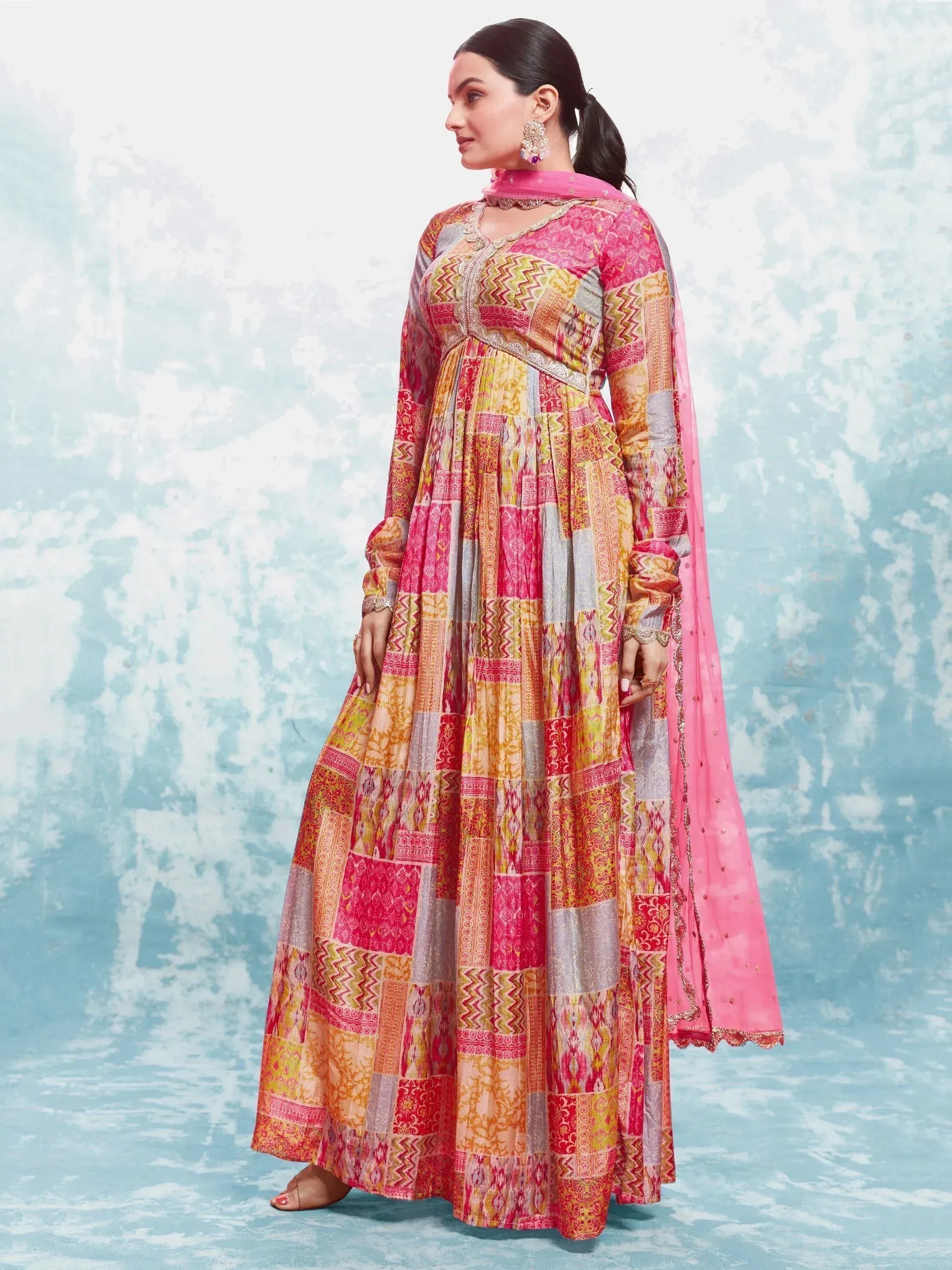 Woman wearing colorful patchwork printed anarkali suit with pink dupatta, Indian ethnic gown