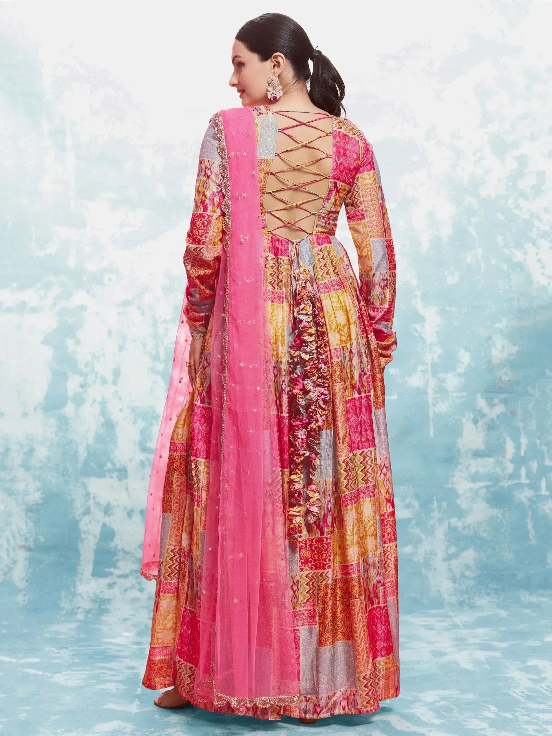 Woman in colorful patchwork ethnic gown with pink dupatta and lace-up open back design