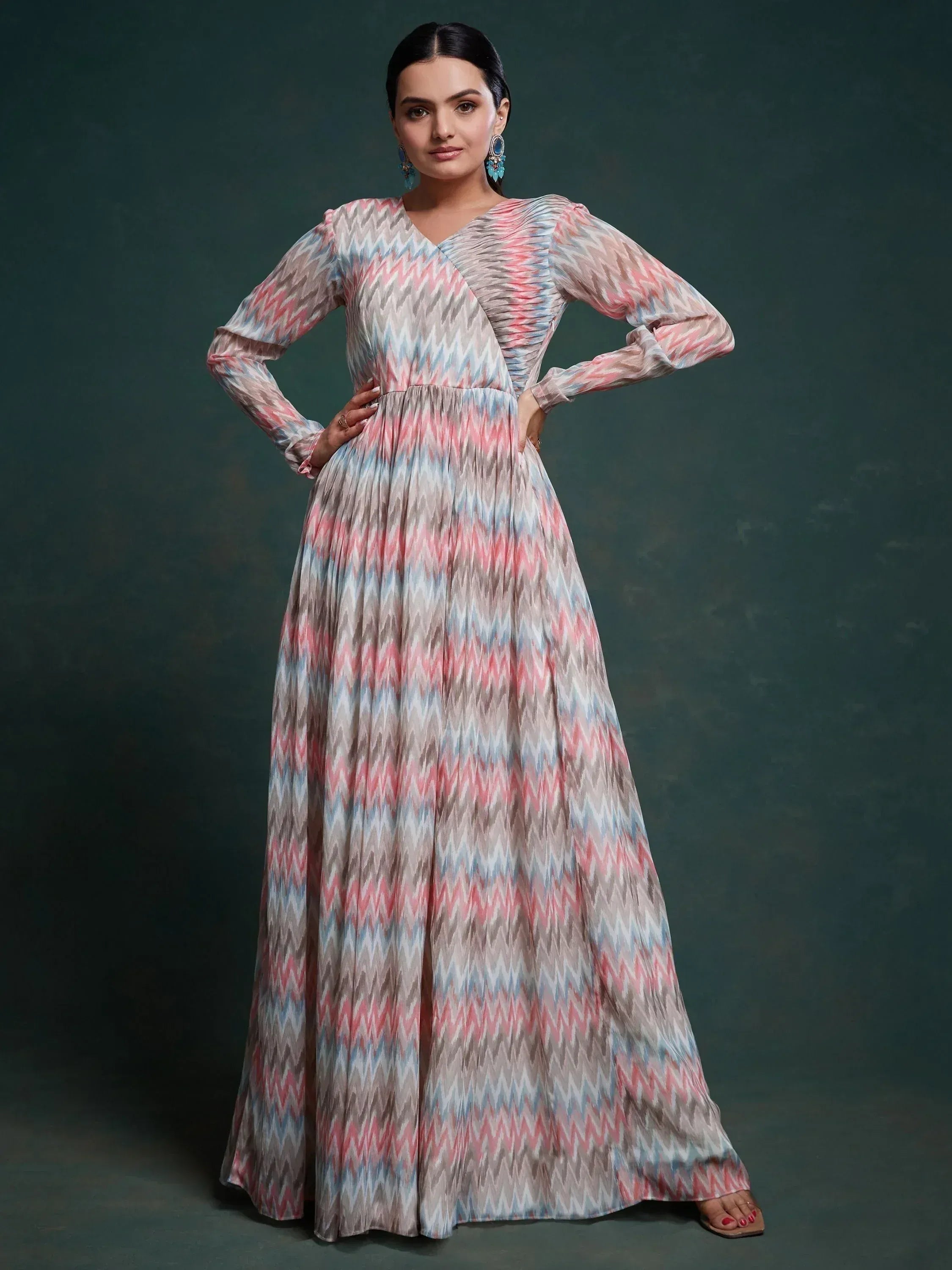 Woman wearing long-sleeve pastel zigzag print ethnic gown, standing against dark background