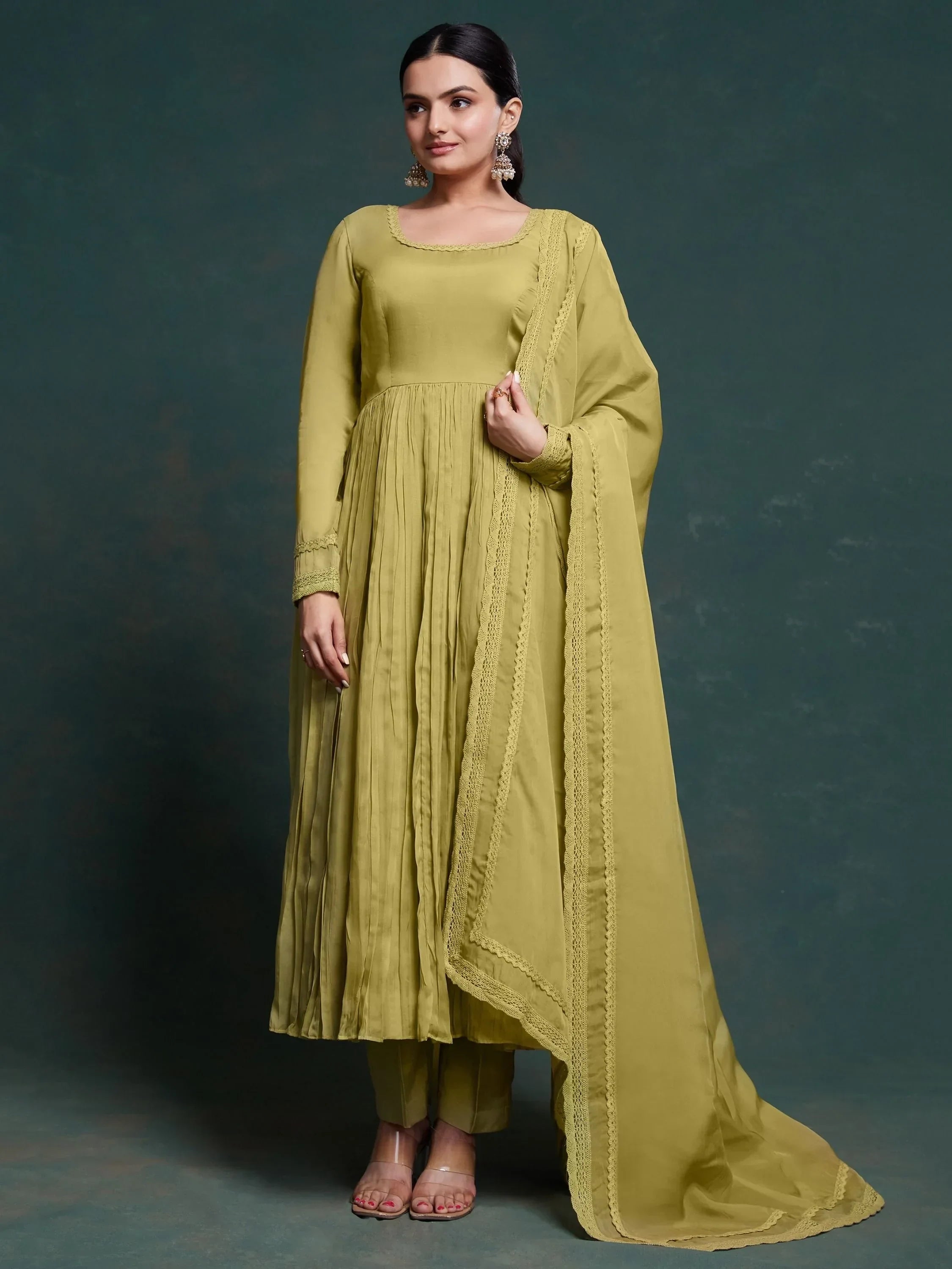 Woman in olive green Anarkali suit with dupatta, long sleeves, and statement earrings