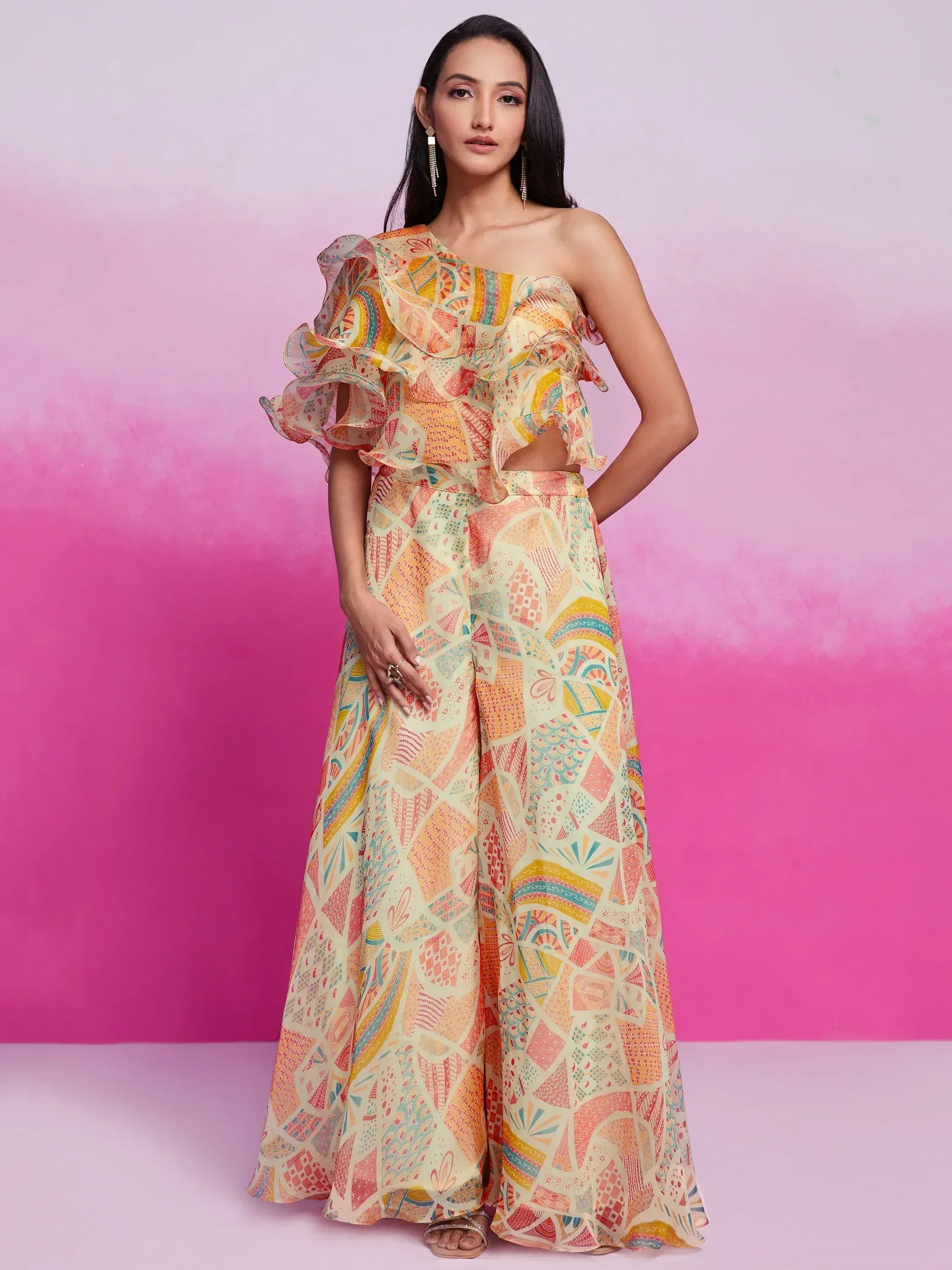 Woman in pastel geometric print ethnic jumpsuit with one-shoulder ruffle sleeve