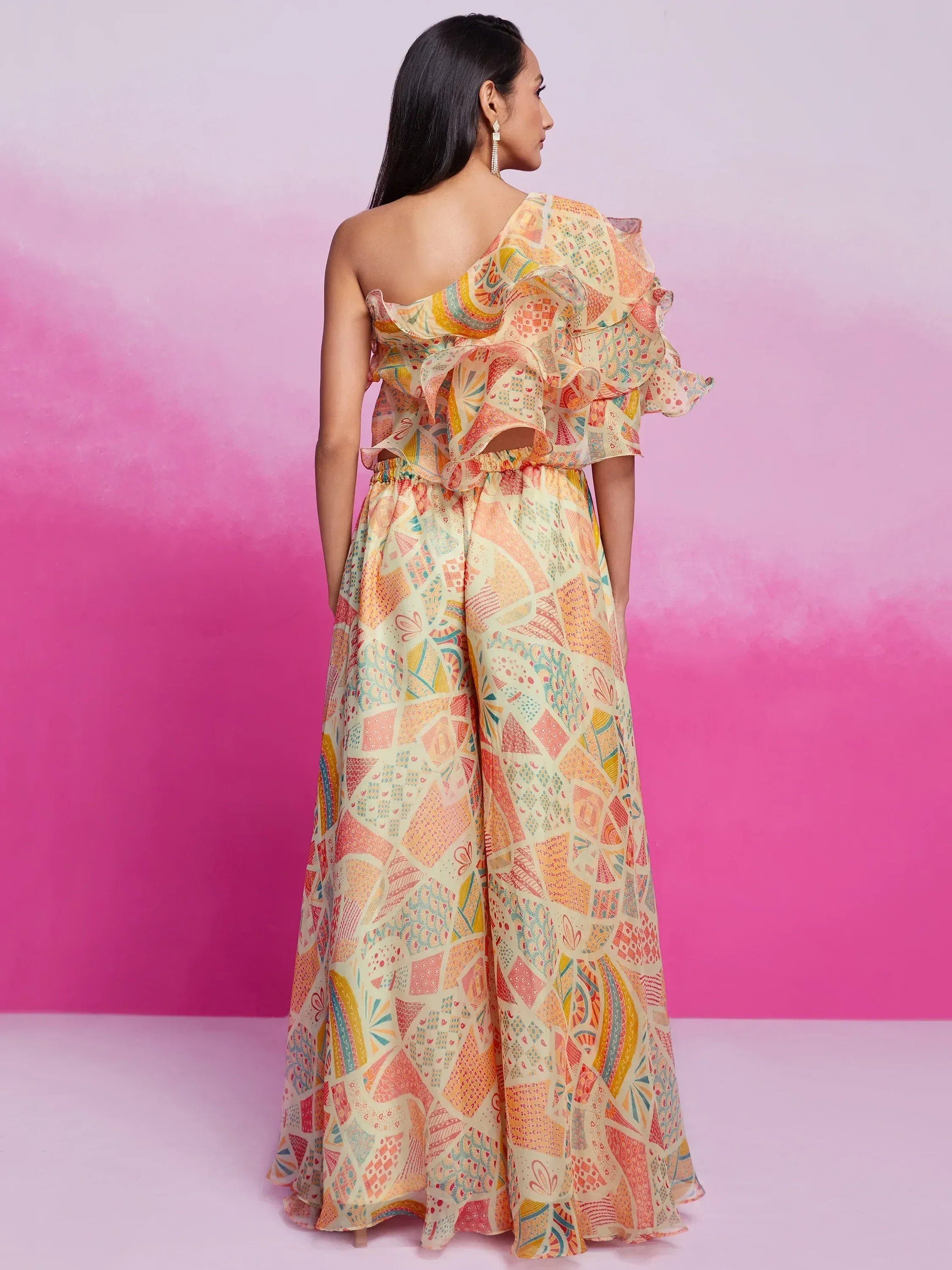 Woman in colorful printed one-shoulder ethnic jumpsuit with flared pants, back view