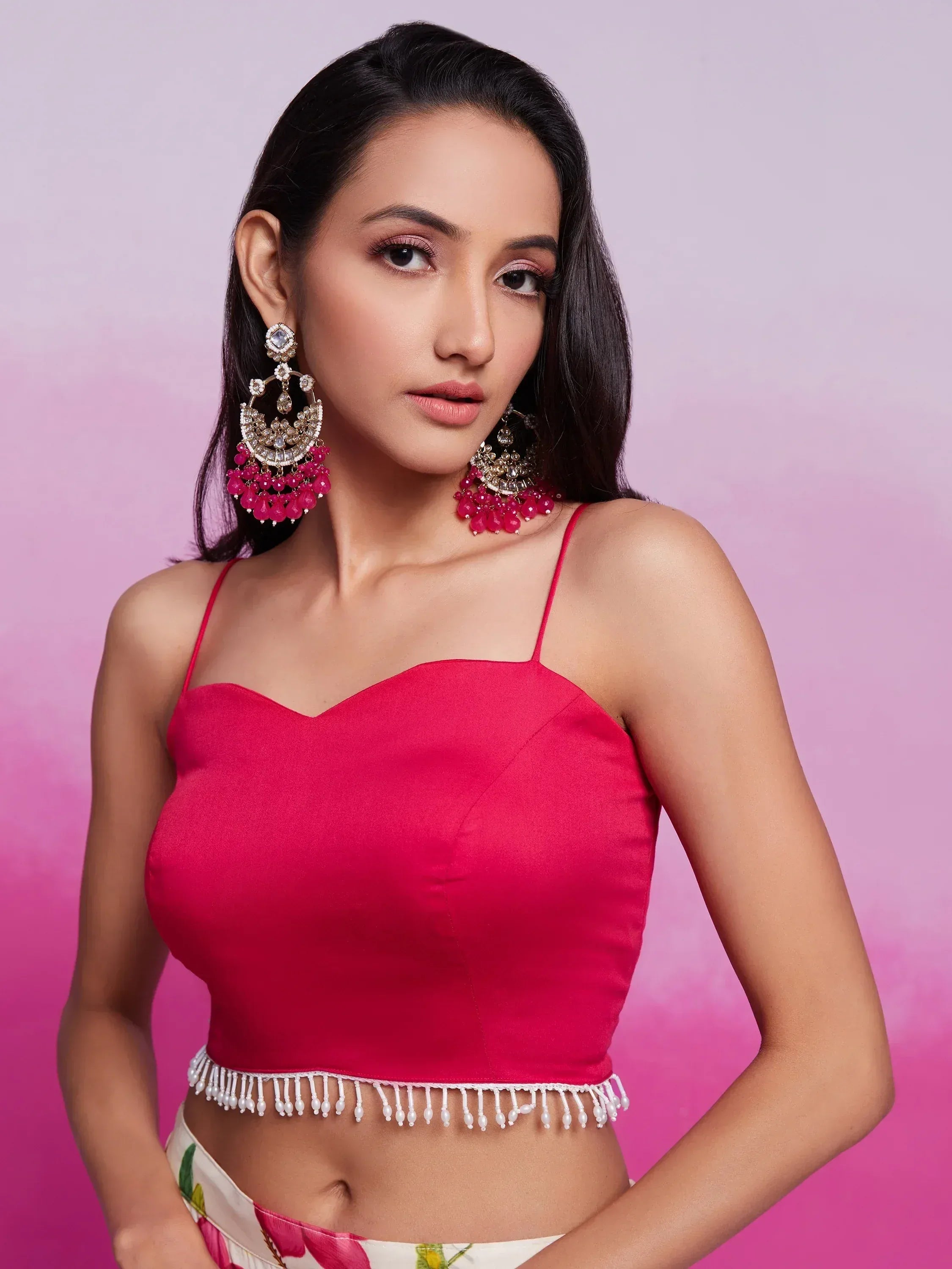 Pink satin crop top with pearl fringe, paired with floral skirt and statement pink earrings for ethnic wear