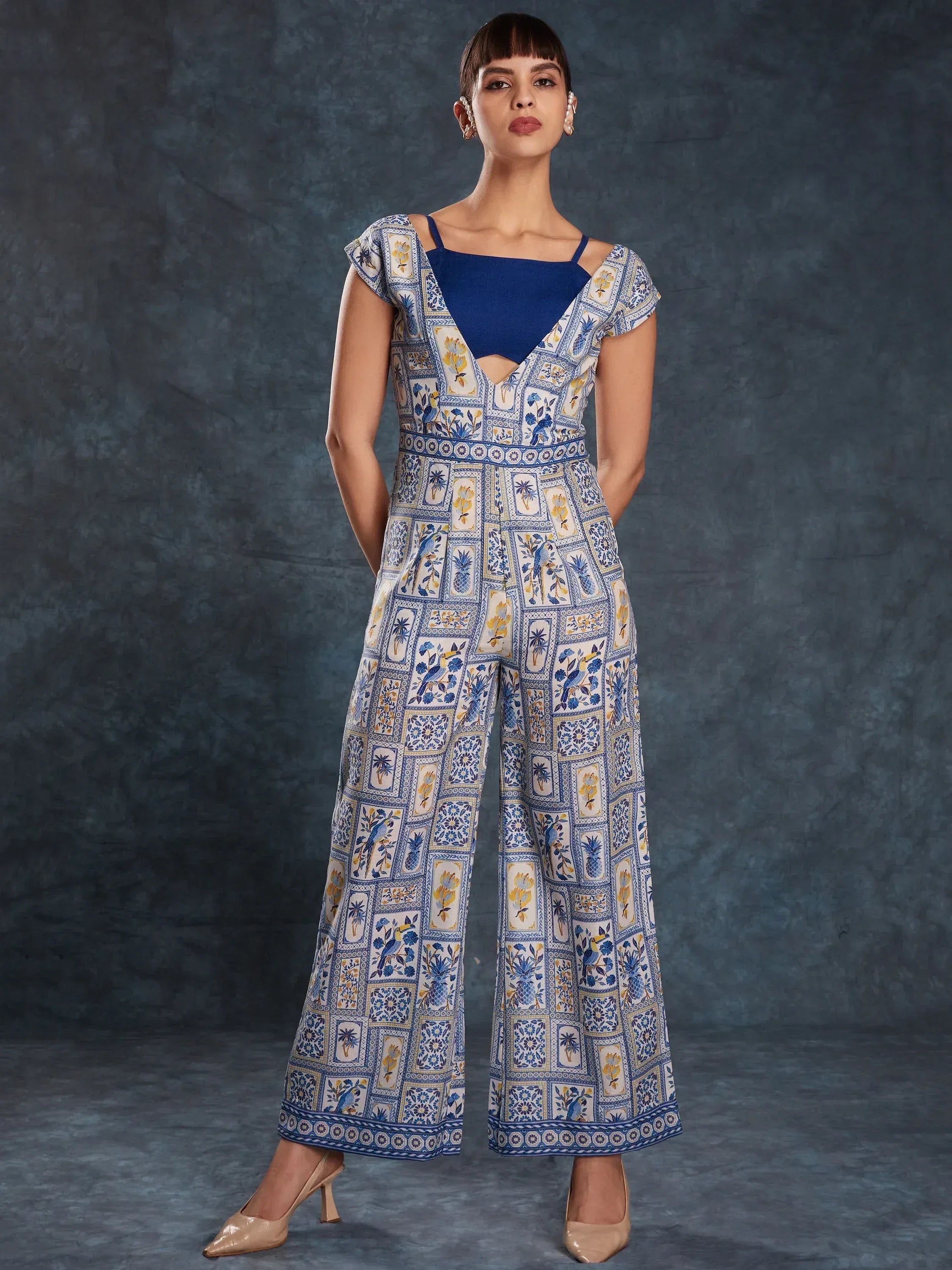 Blue and white printed ethnic jumpsuit with floral and bird motifs, wide-leg design, and square neckline.